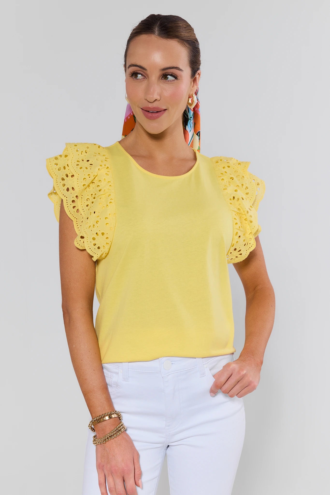 Woman wearing a yellow top with ruffled sleeves against a white background
