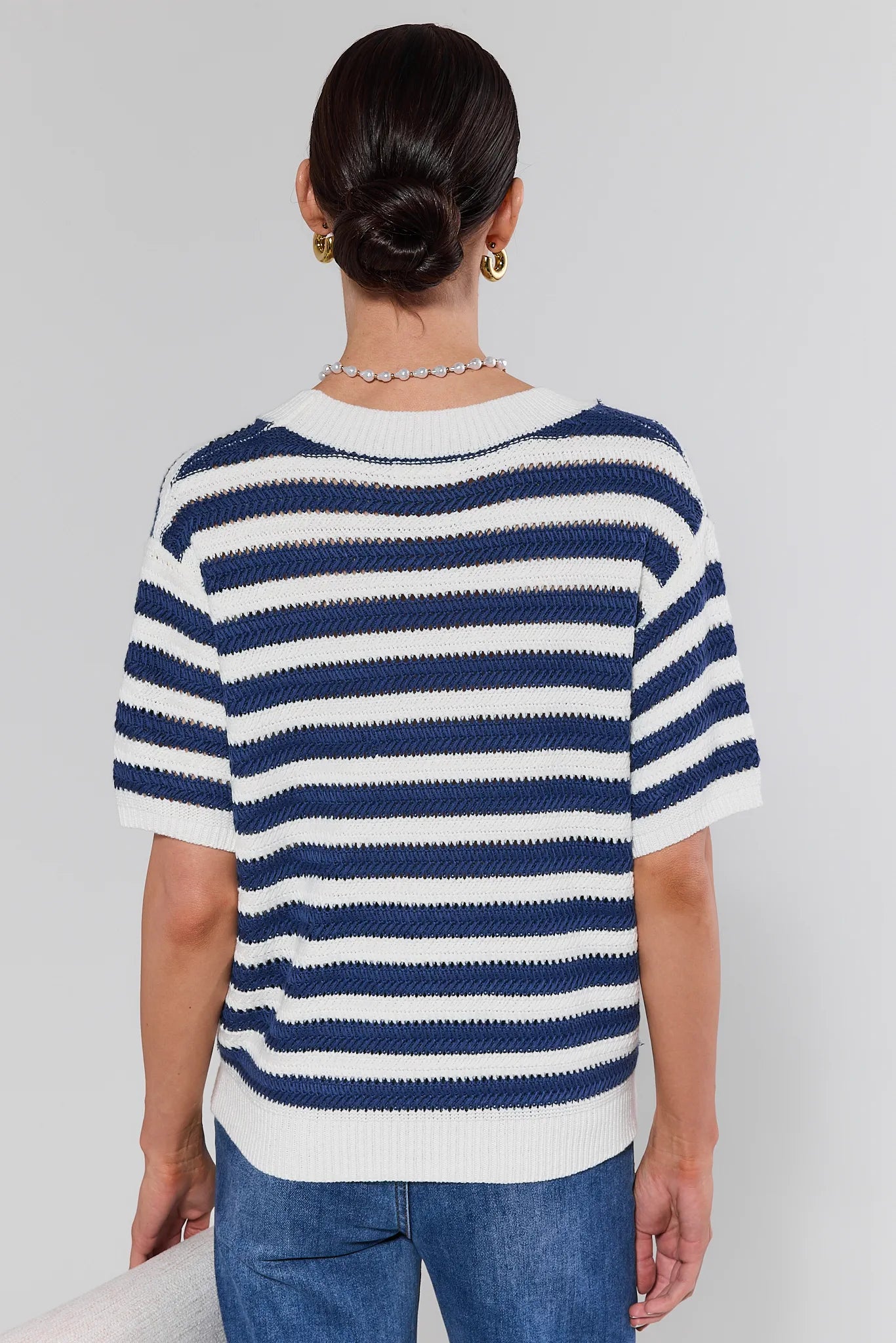 Person wearing a blue and white striped sweater against a plain background