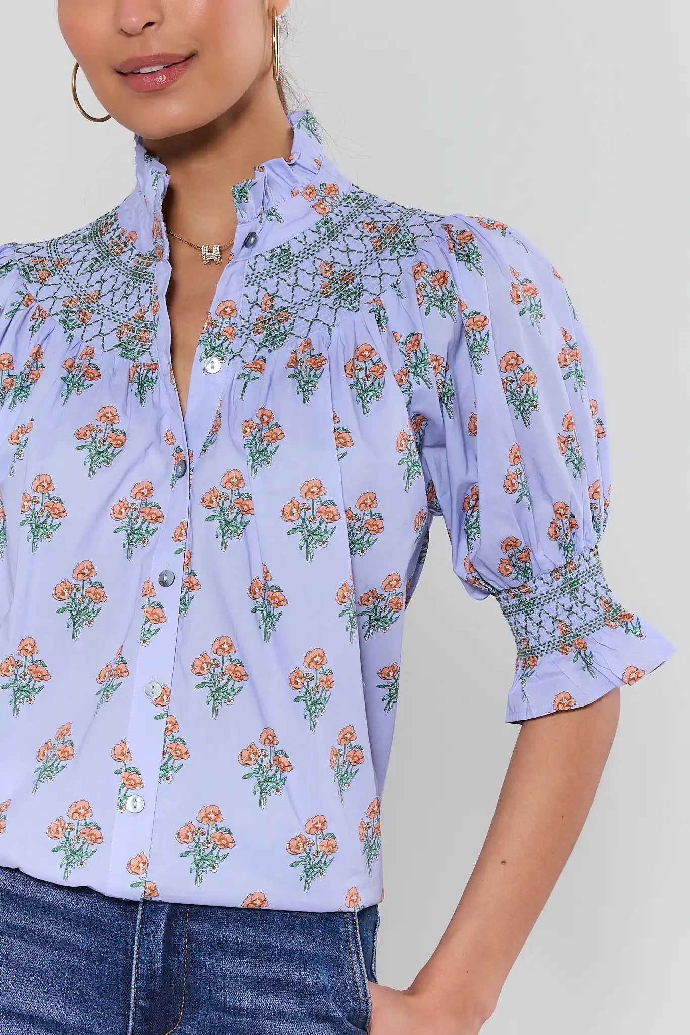 Woman wearing a light blue floral blouse with a plain background