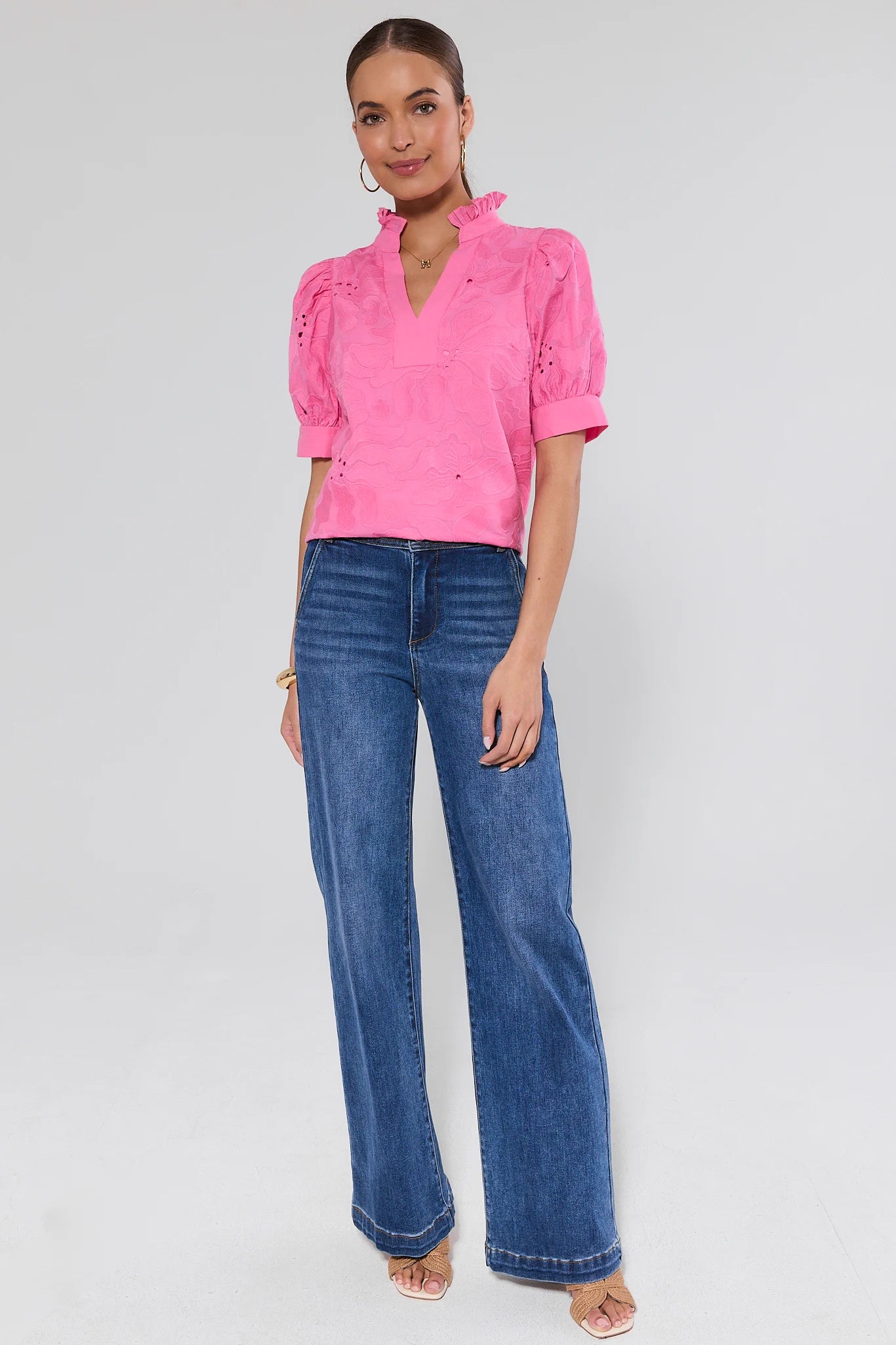 Woman wearing a pink blouse and blue jeans on a gray background