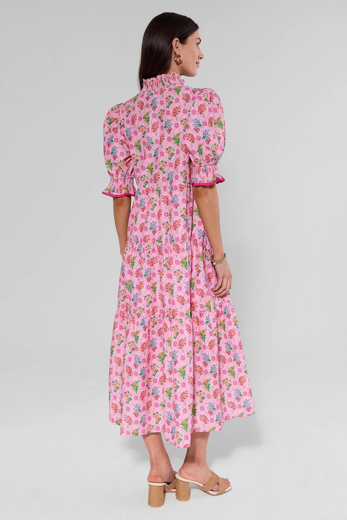 Woman wearing a pink floral dress on a gray background