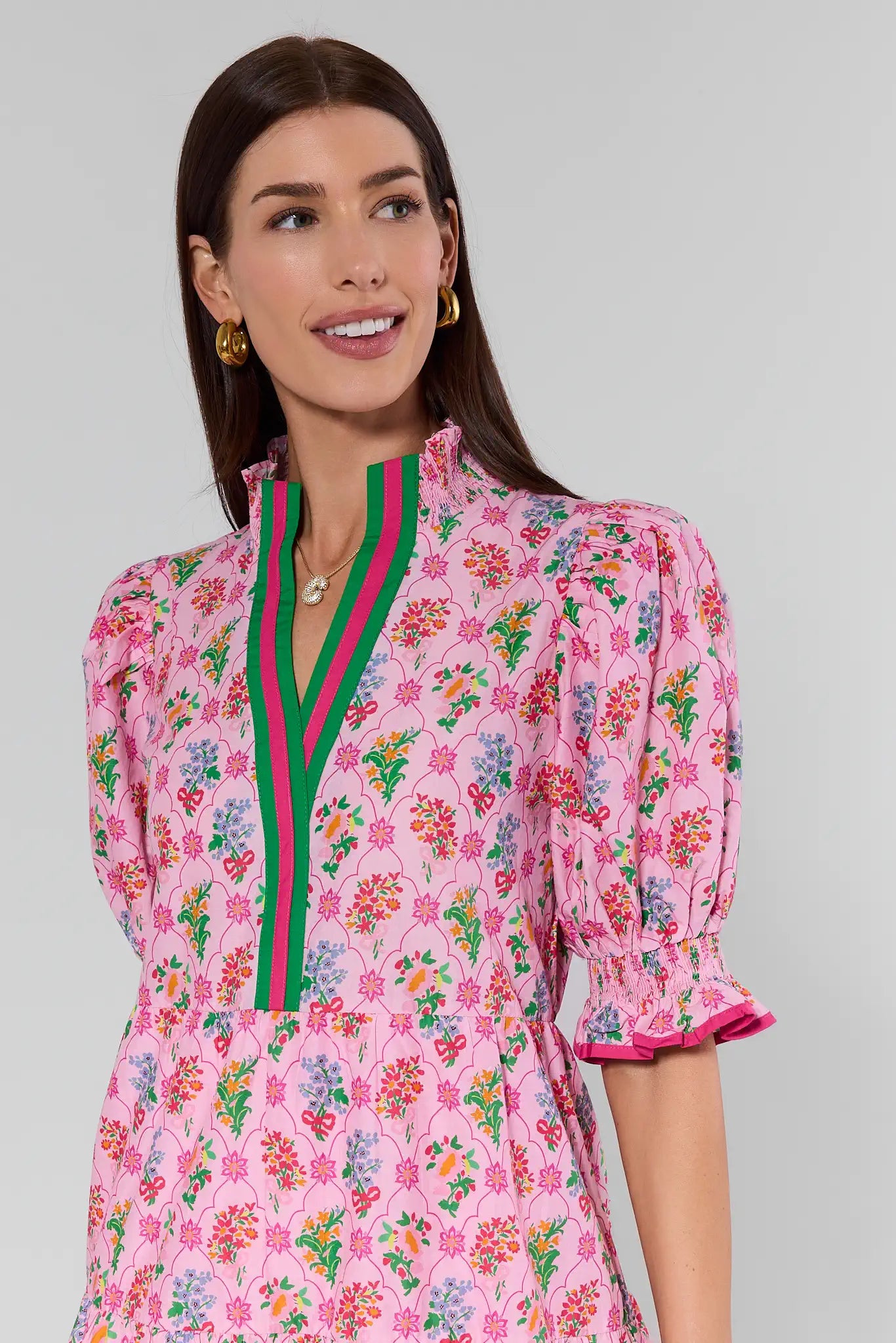 Woman wearing a pink floral dress with a green and red stripe on a gray background