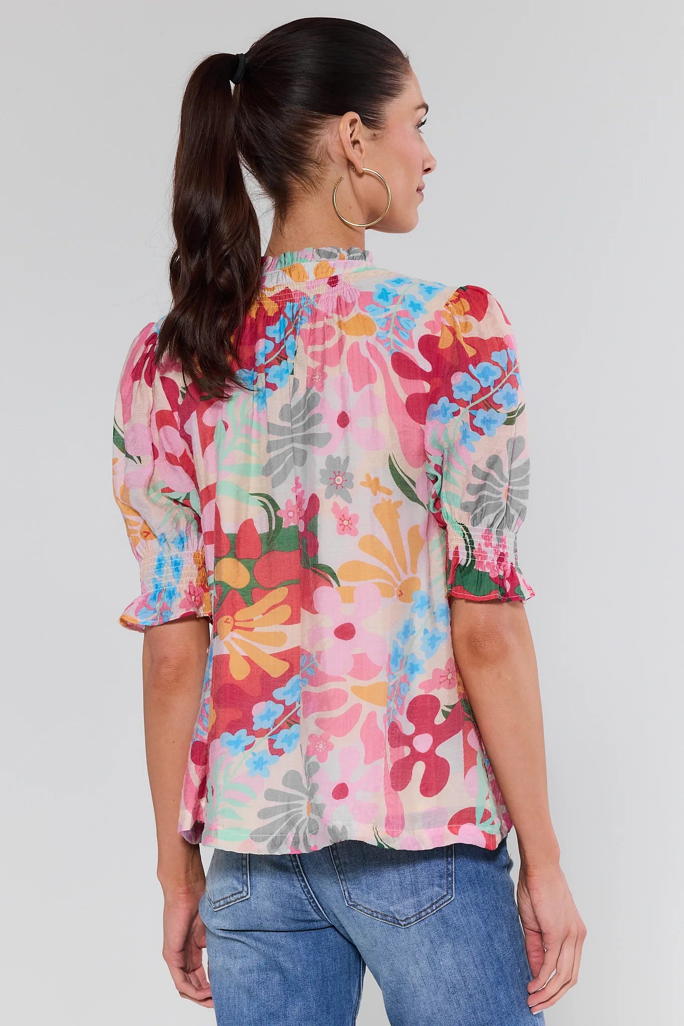 Woman wearing a colorful floral blouse against a plain background