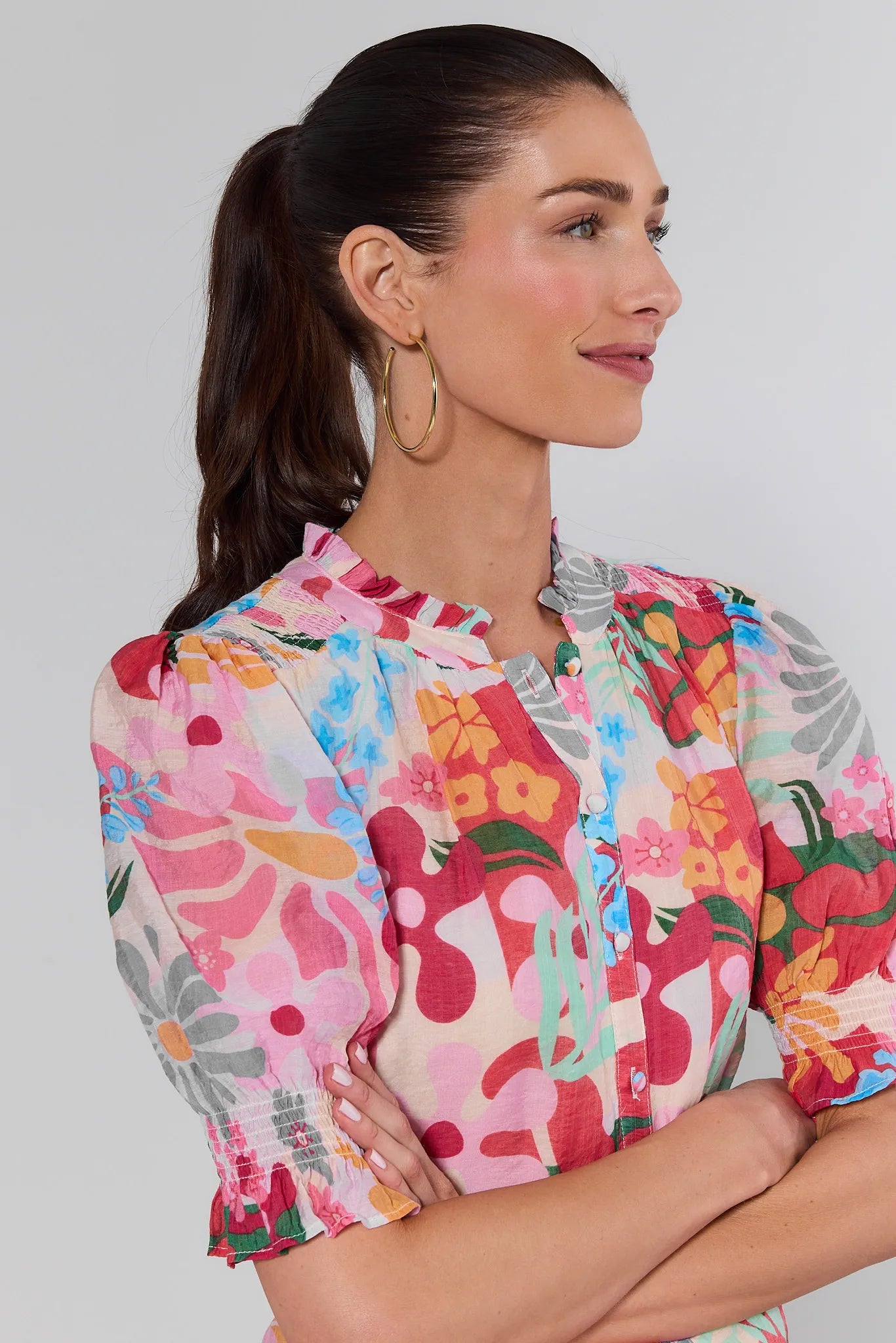 Woman wearing a colorful floral blouse against a plain background