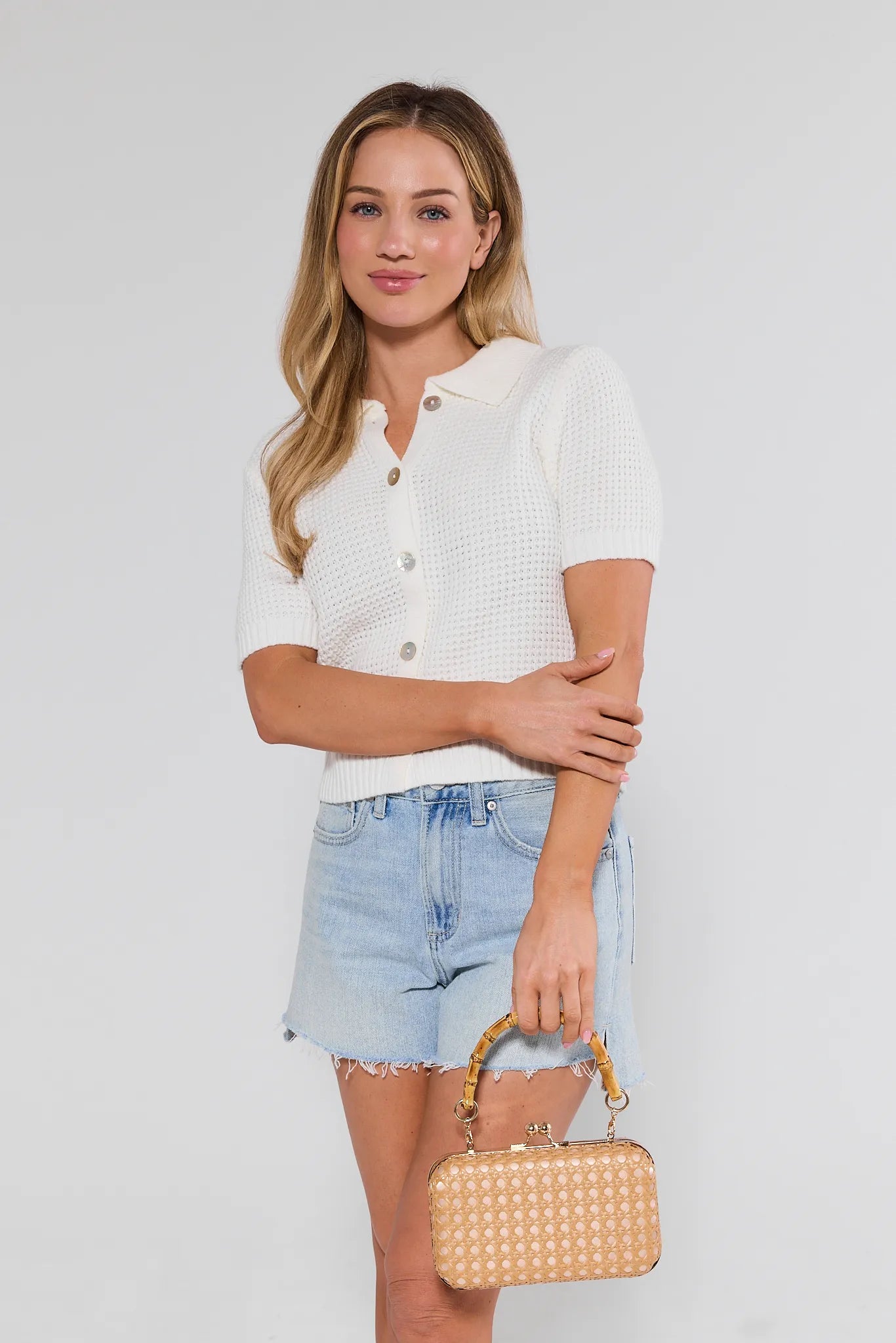 Woman holding a gold handbag against a plain background