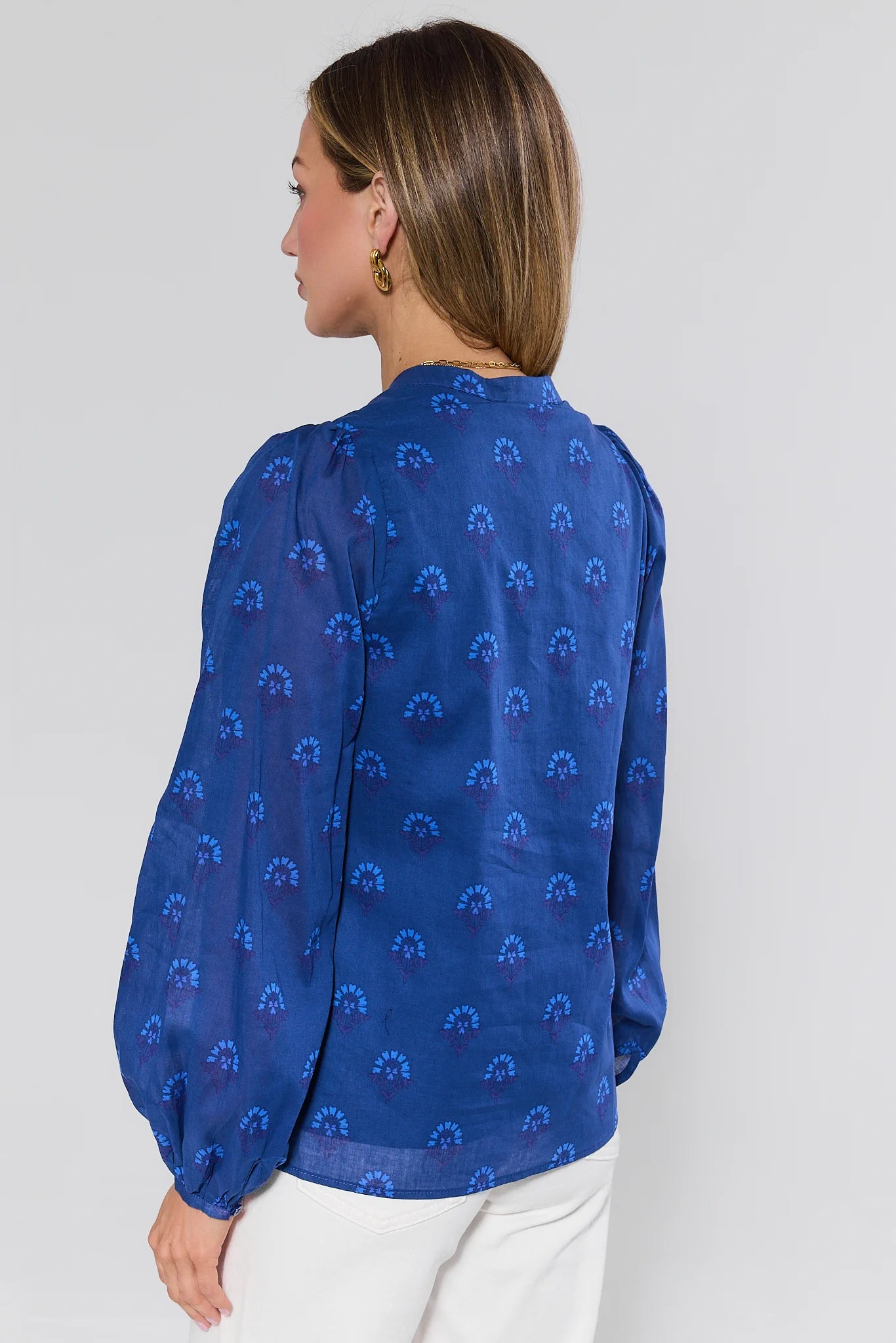 Woman wearing a blue patterned blouse against a white background