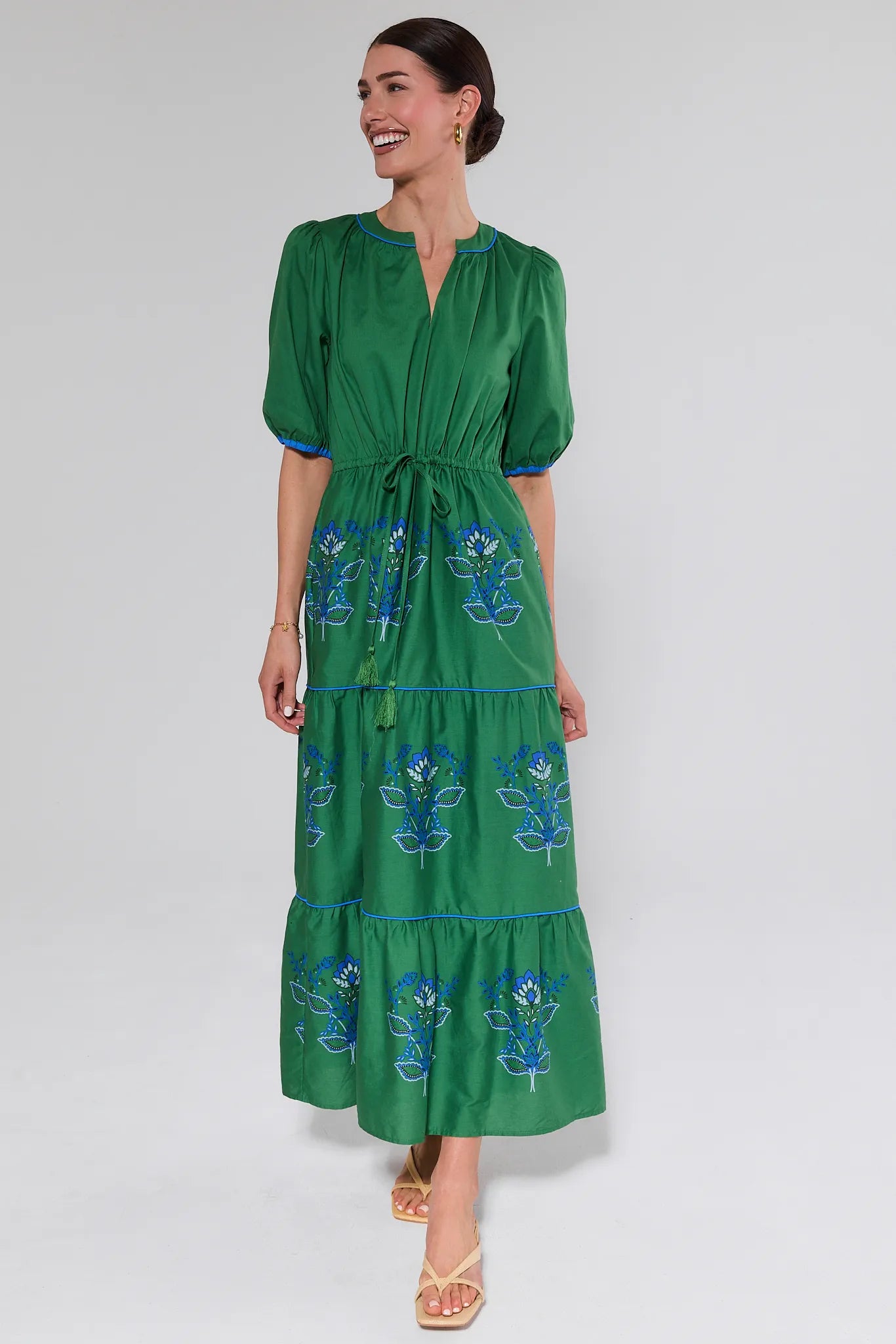 Woman wearing a green dress with floral embroidery on a white background