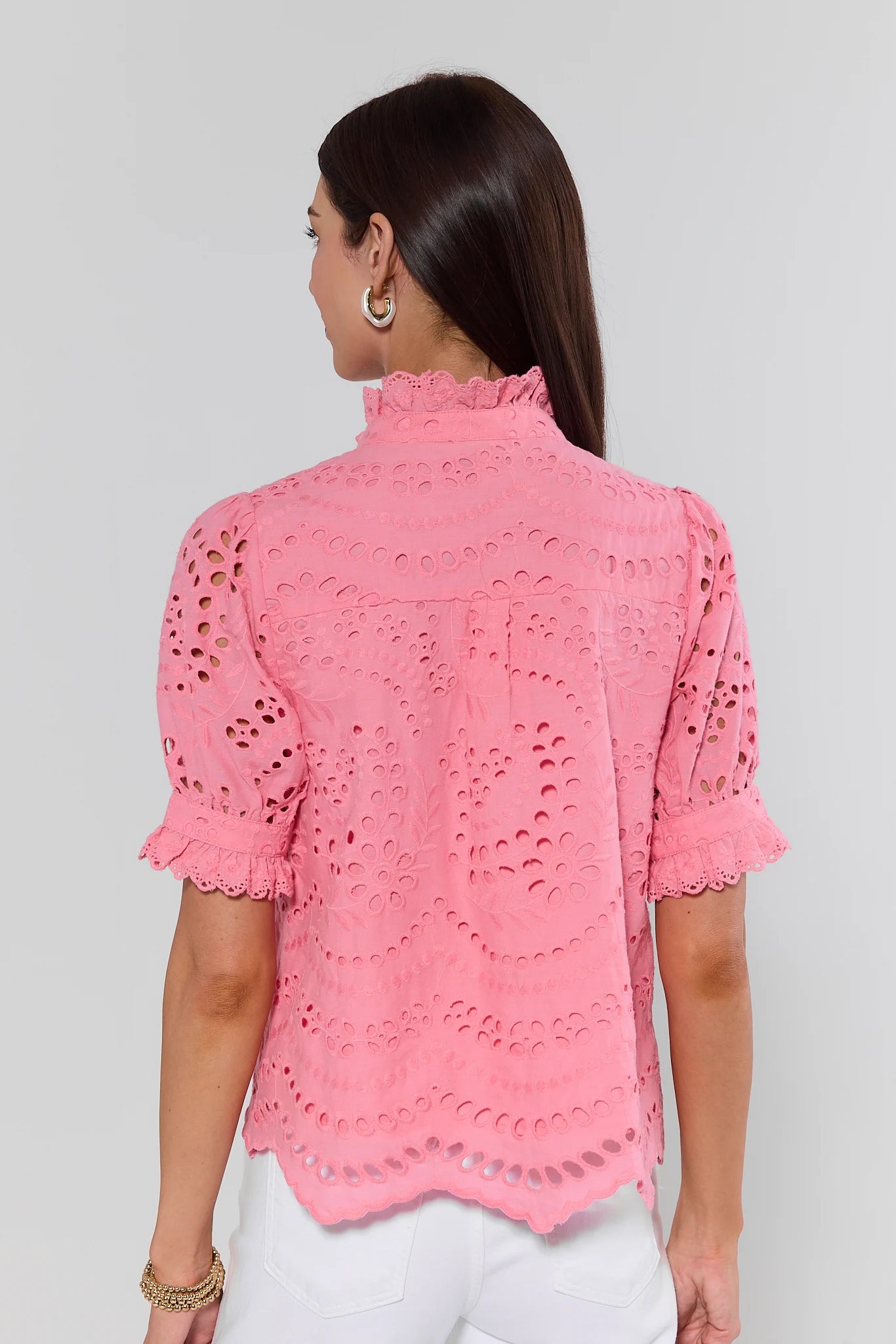 Woman wearing a pink lace top against a gray background