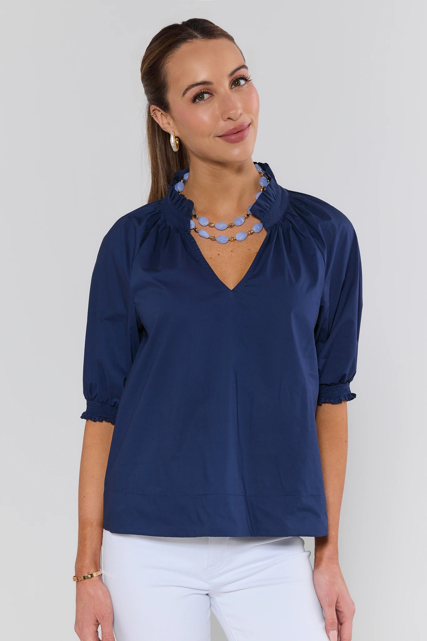 Woman wearing a blue blouse with a necklace against a white background