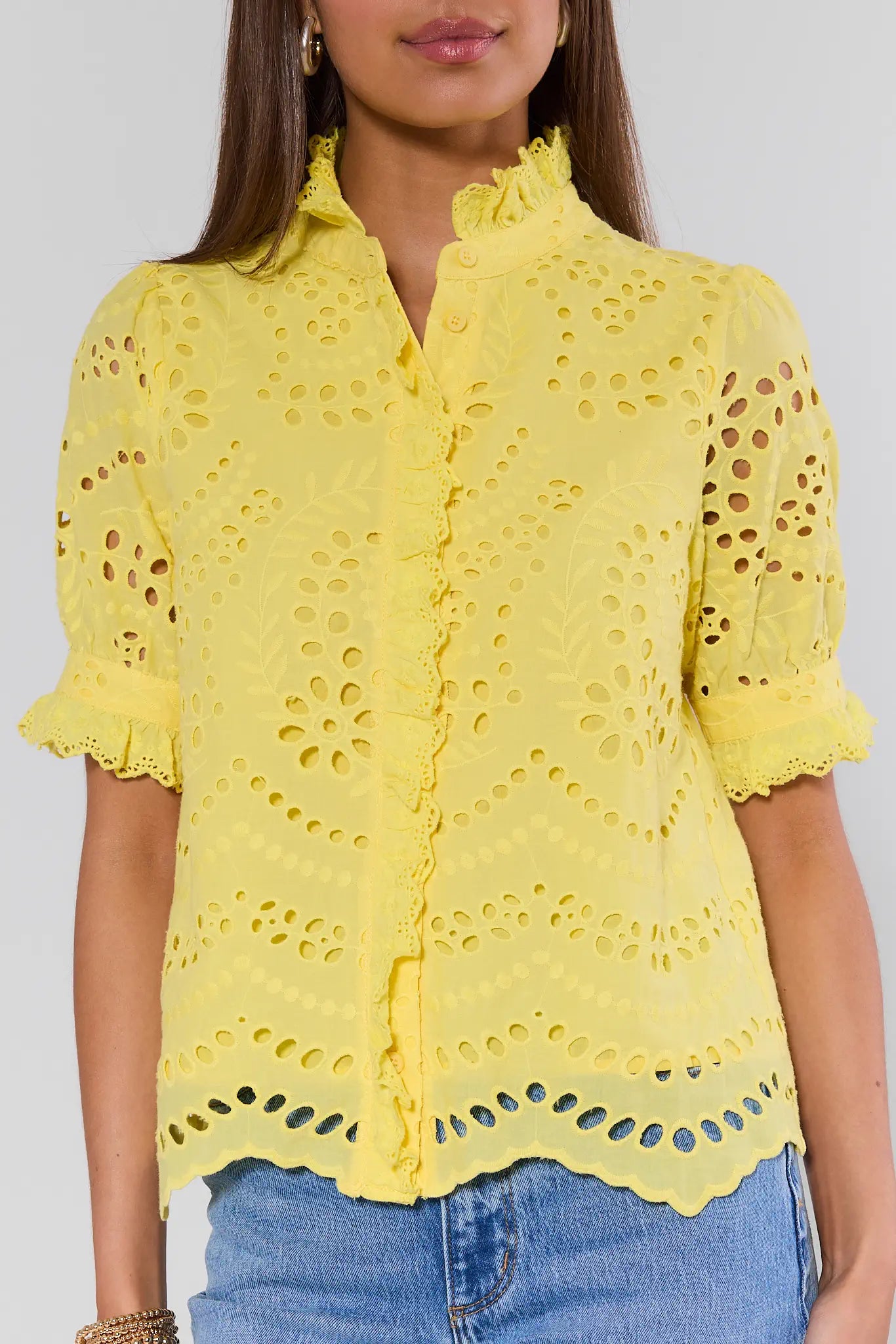 Yellow lace blouse worn by a person on a plain background
