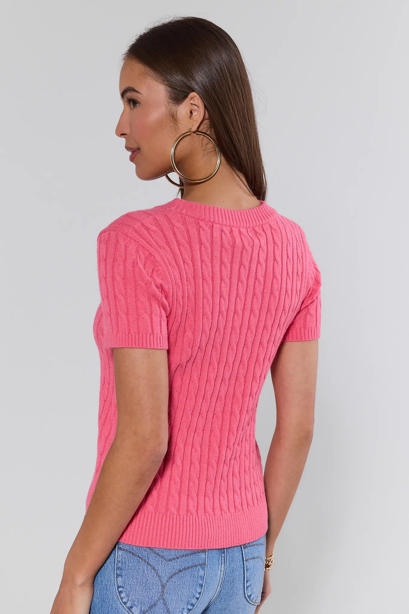 Woman wearing a pink knitted top against a plain background