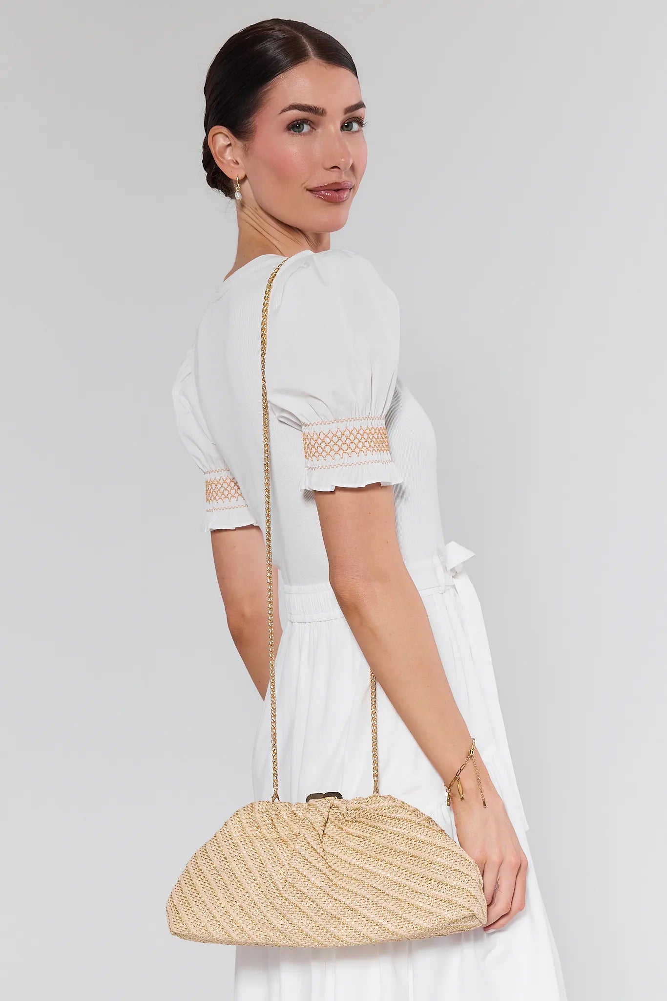 Woman holding a woven handbag against a plain background