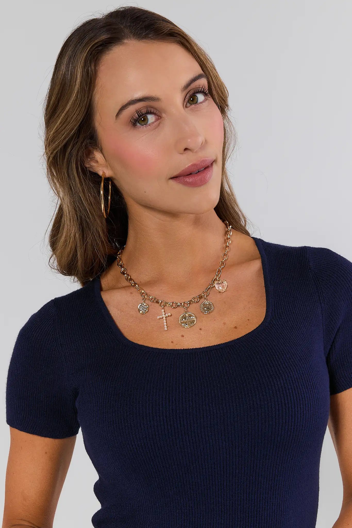 Woman wearing a navy blue top with a necklace against a plain background