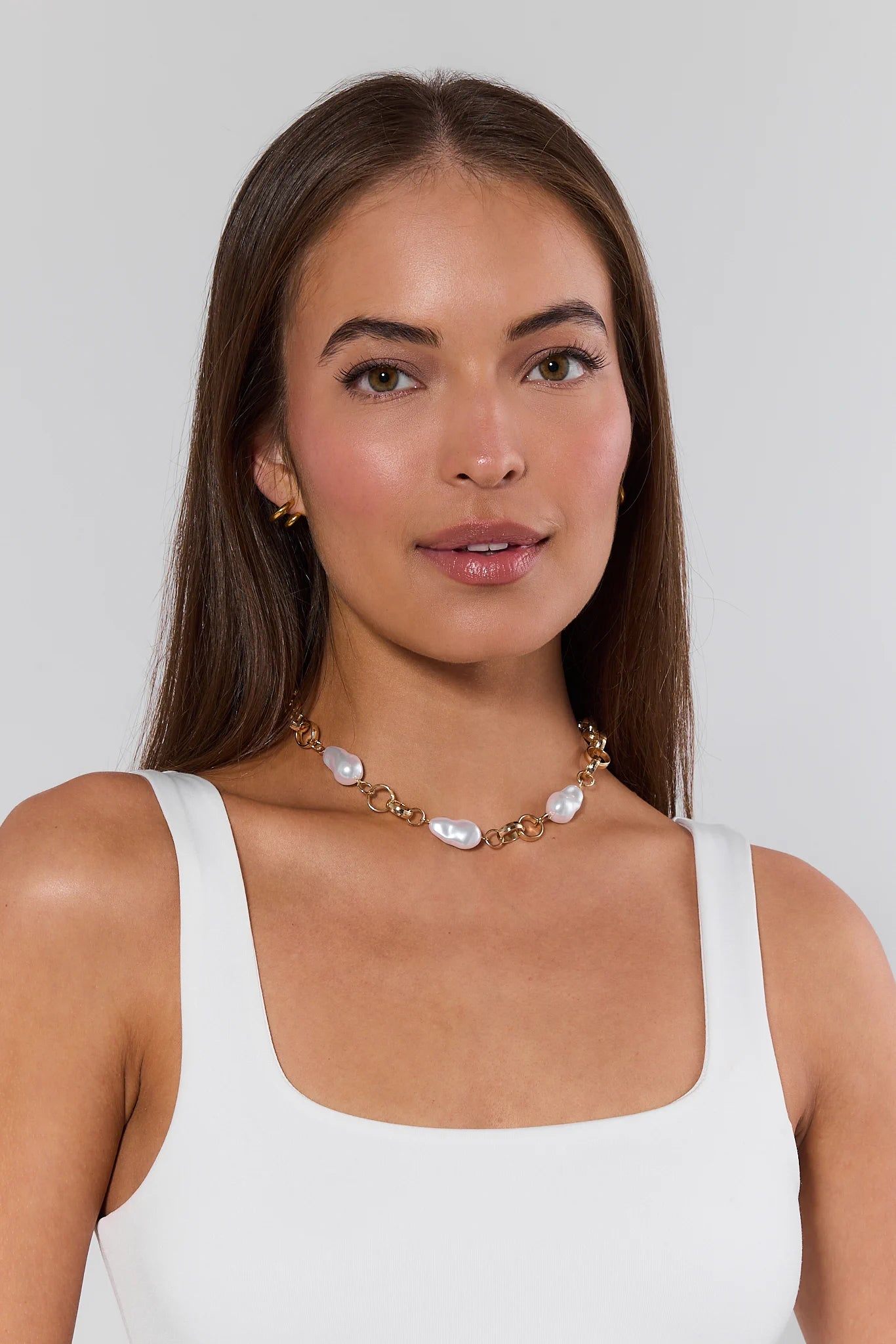 Woman wearing a pearl necklace against a plain background