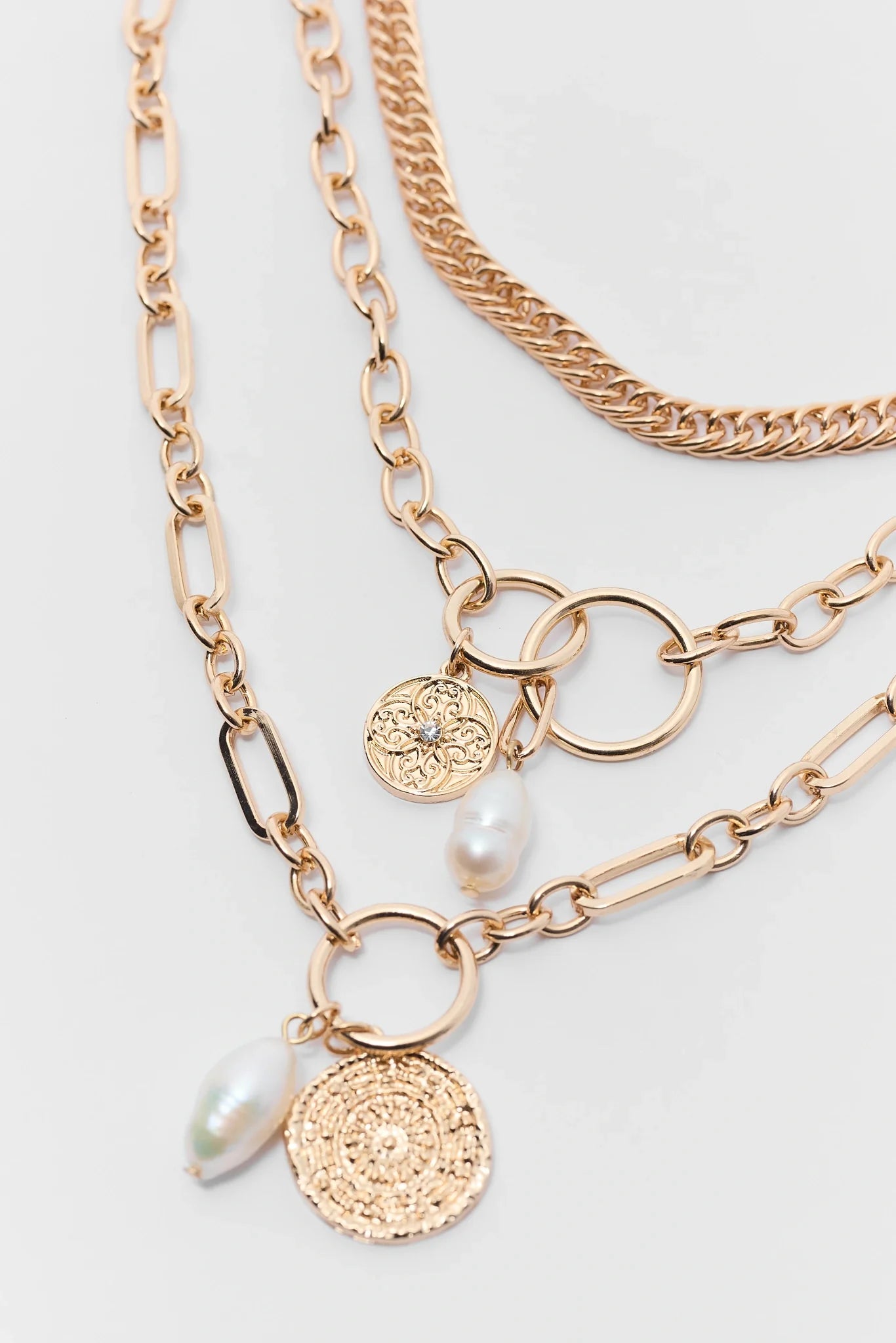 Gold necklaces with various pendants on a light gray background