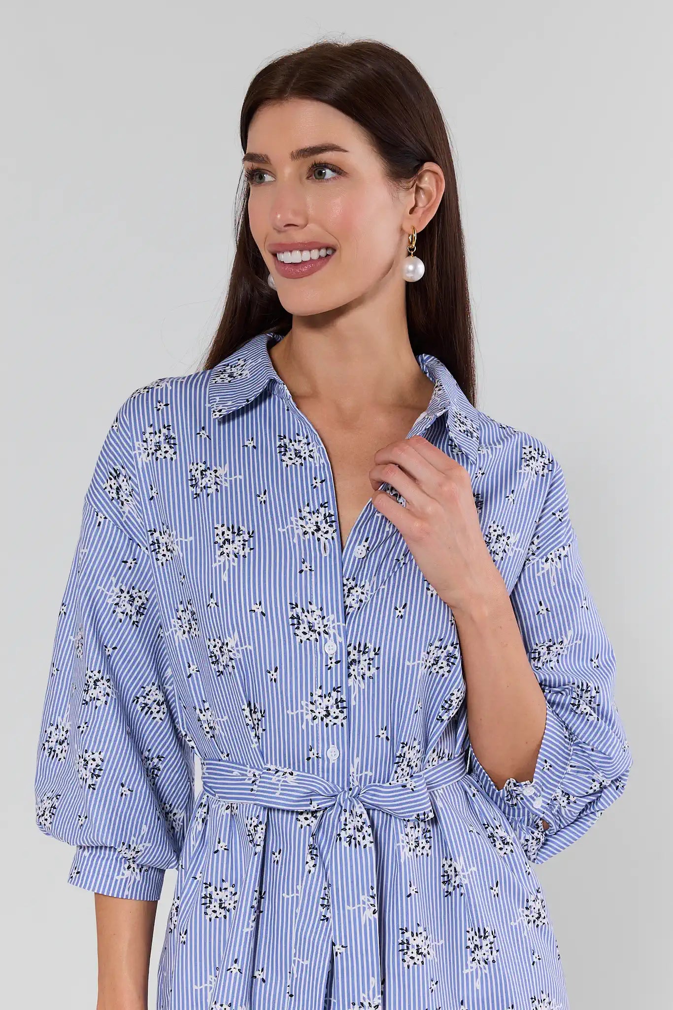 Woman wearing a blue floral dress against a gray background