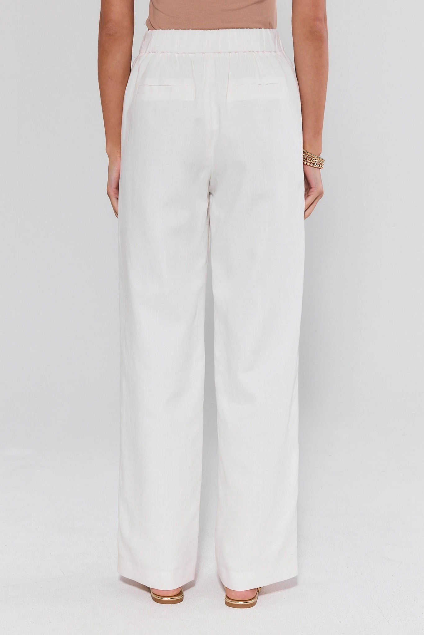 Person wearing white pants on a plain background