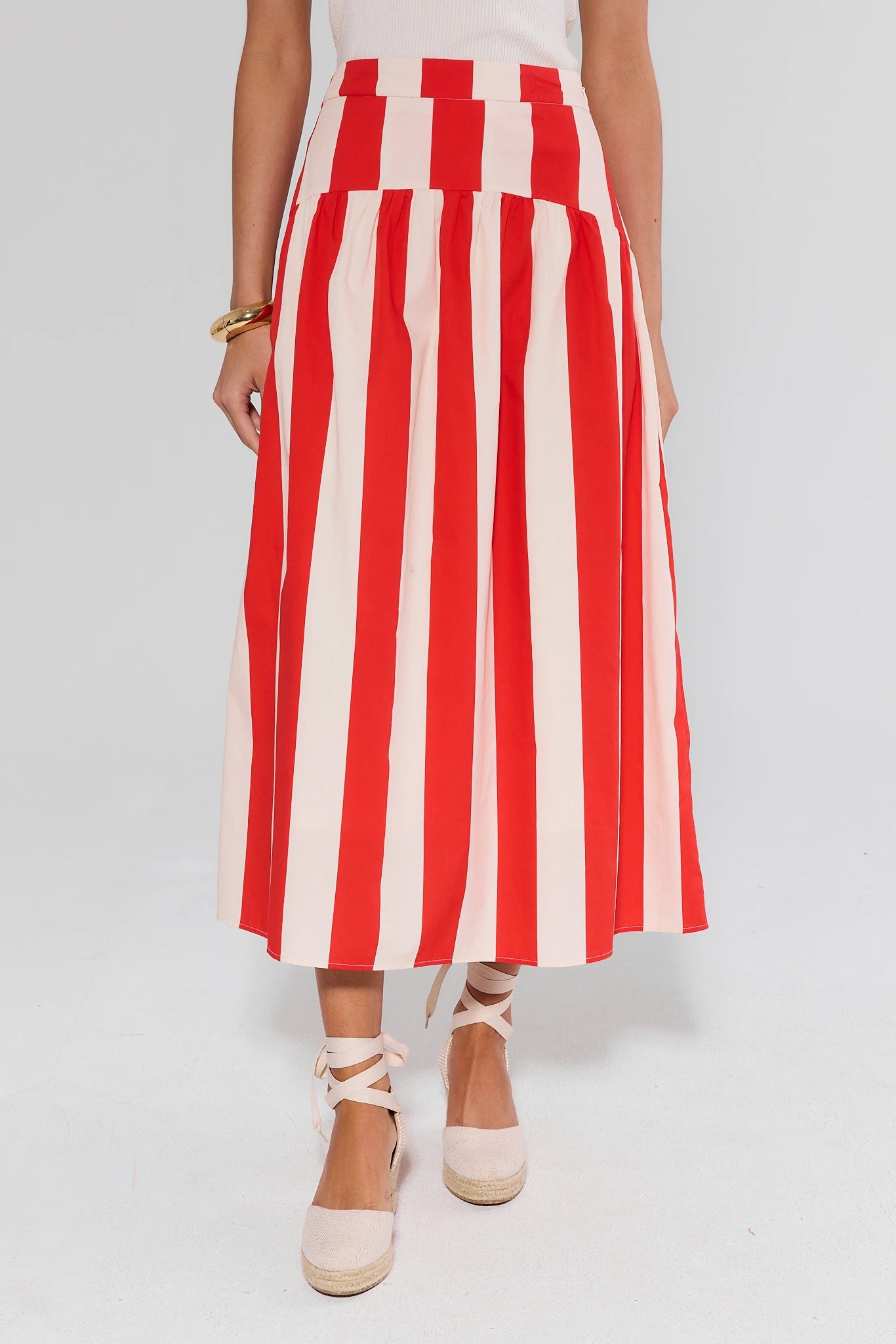 Red and white striped skirt worn by a person on a plain background