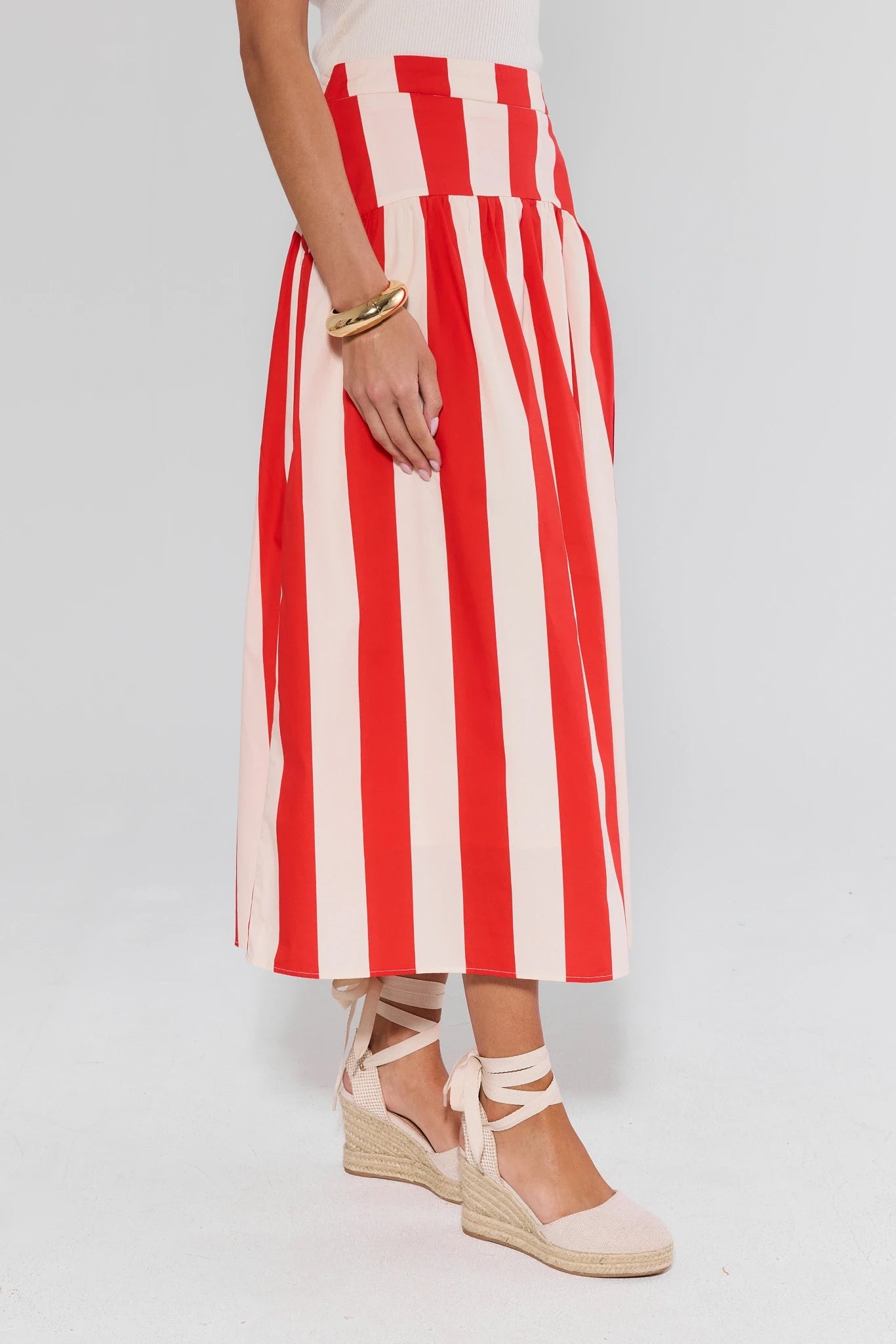 Red and white striped skirt worn by a person on a plain background