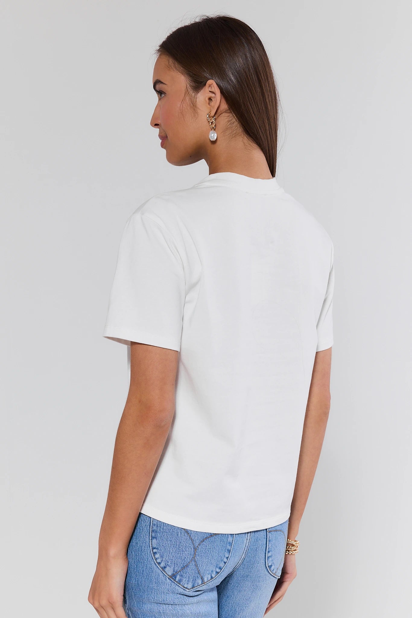 Person wearing a white t-shirt and blue jeans on a plain background