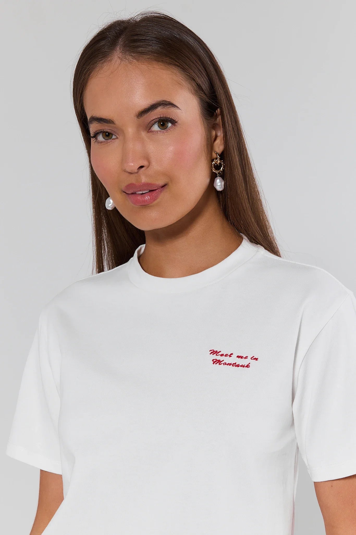 Woman wearing a white t-shirt with red text on a plain background