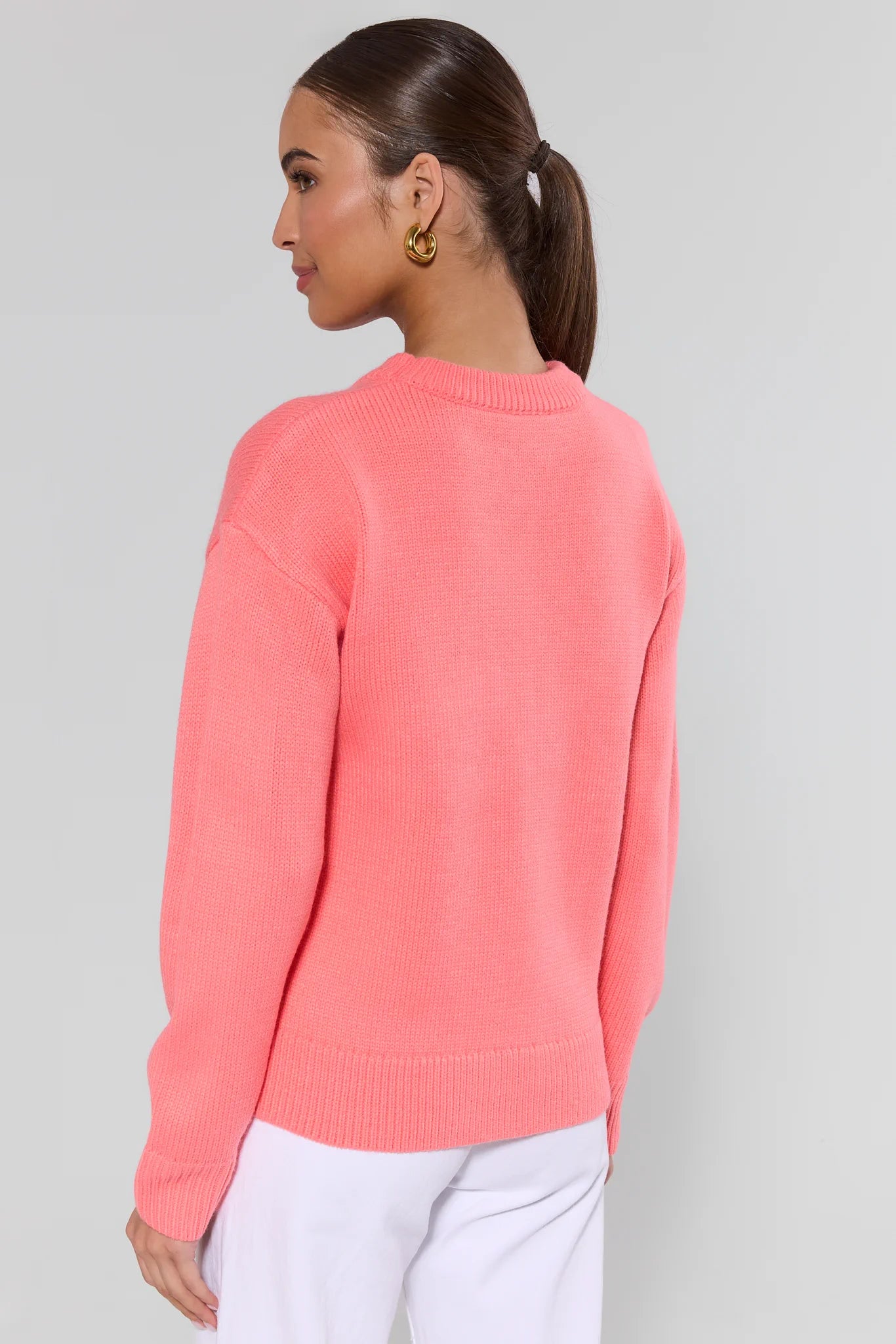 Woman wearing a pink sweater against a gray background