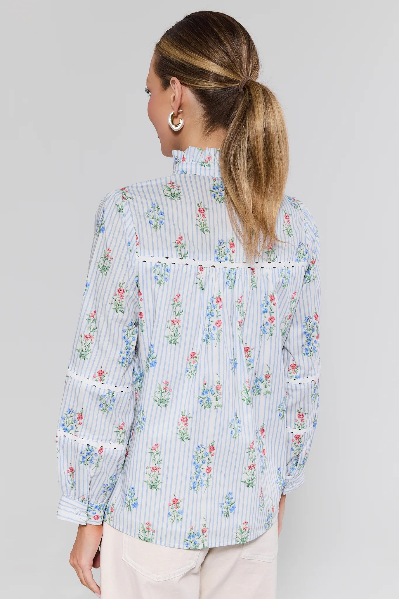 Woman wearing a floral and striped blouse against a plain background
