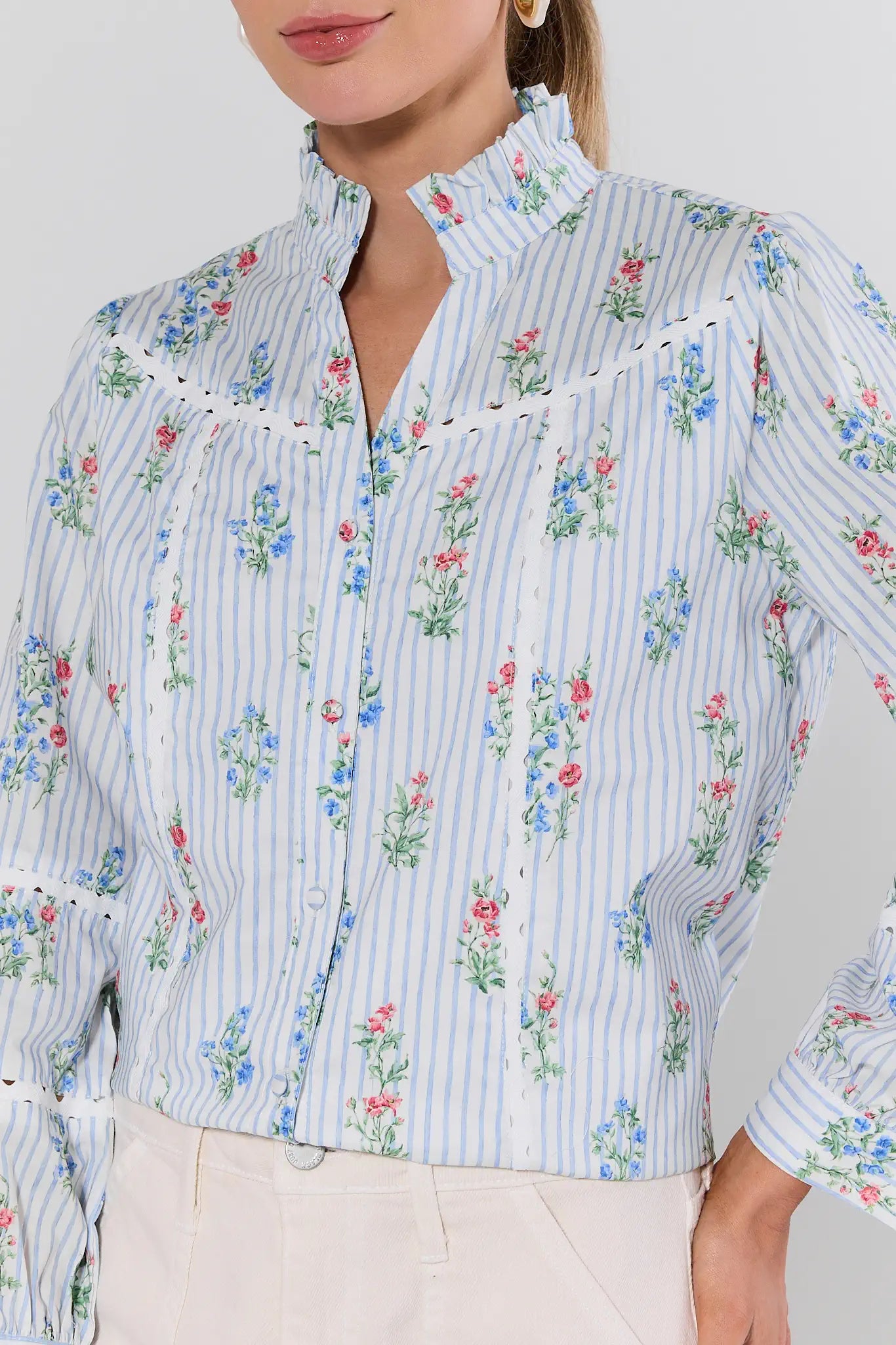 Woman wearing a floral and striped blouse against a plain background