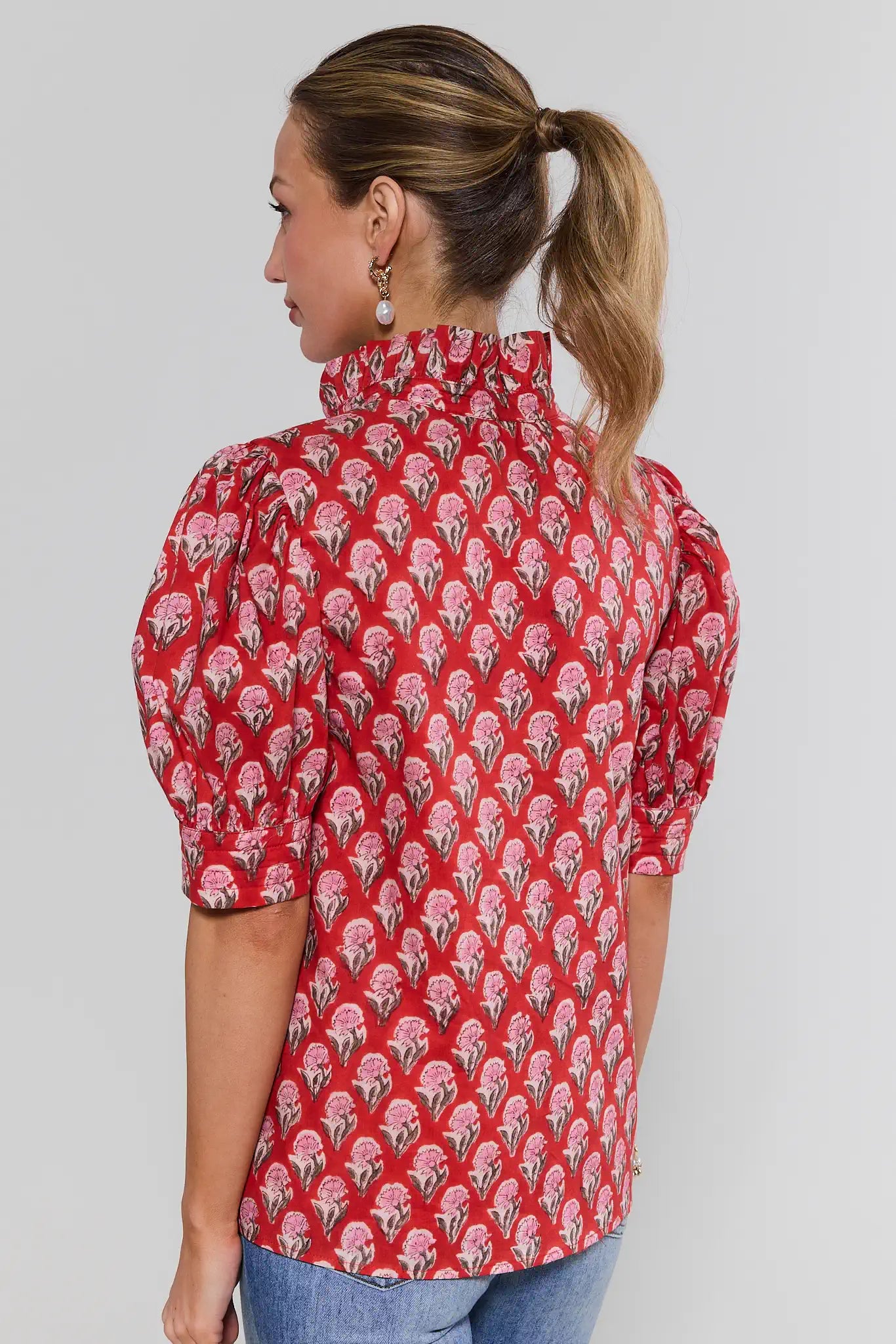 Woman wearing a red floral patterned blouse against a gray background