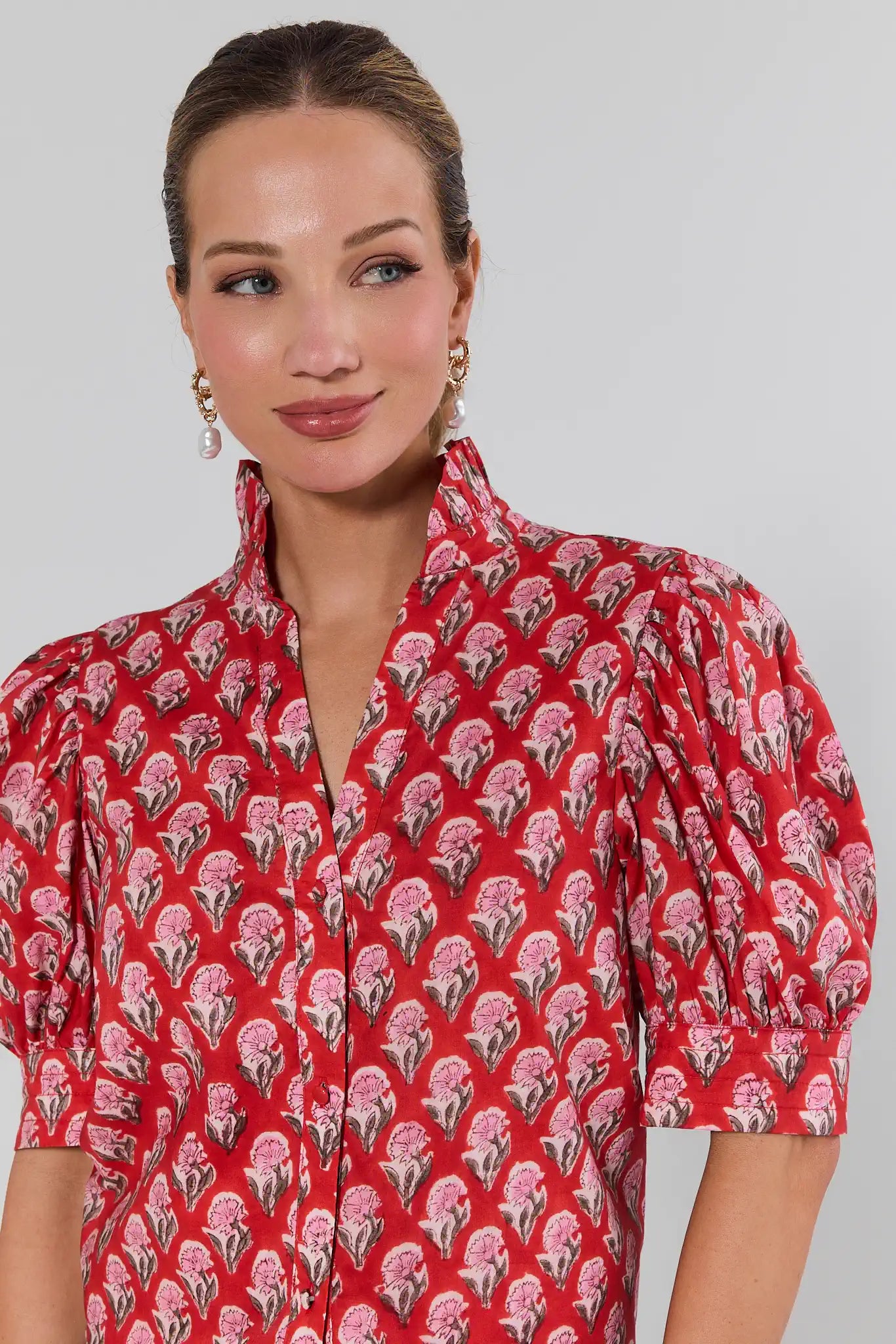 Woman wearing a red floral patterned dress against a plain background
