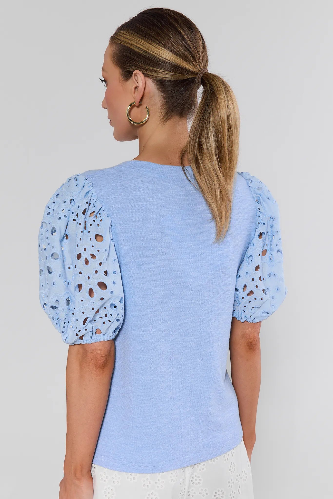 Woman wearing a light blue top with puff sleeves against a plain background