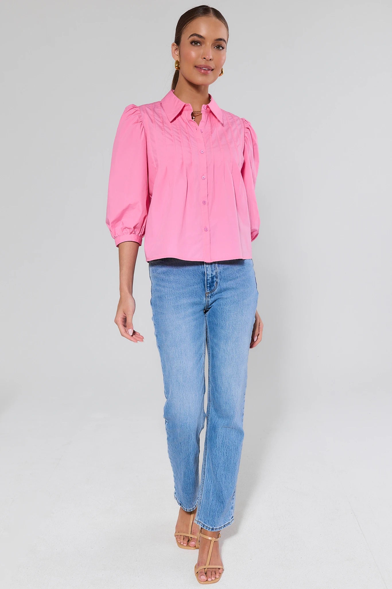 Woman wearing a pink blouse and blue jeans on a gray background