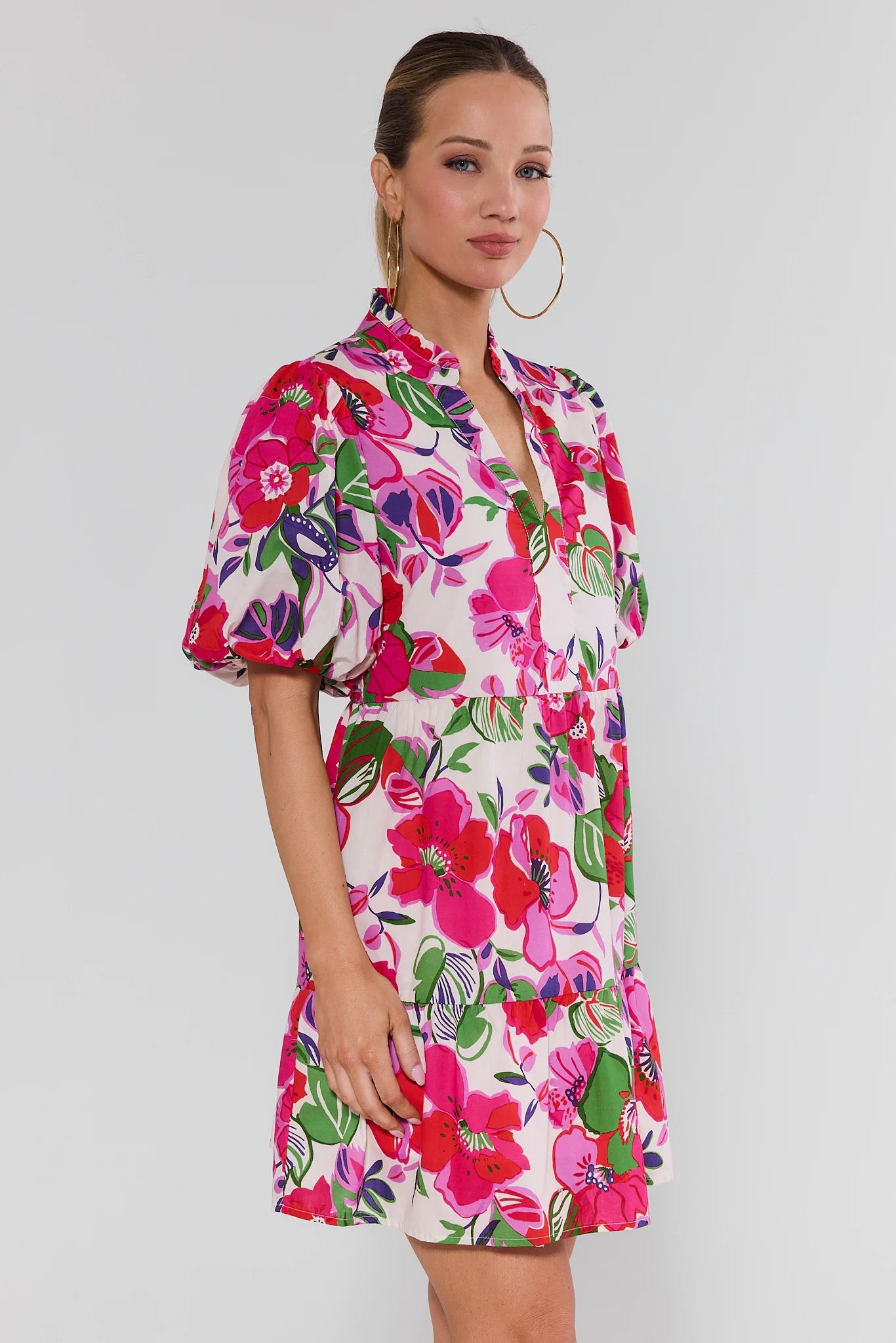 Woman wearing a colorful floral dress on a plain background