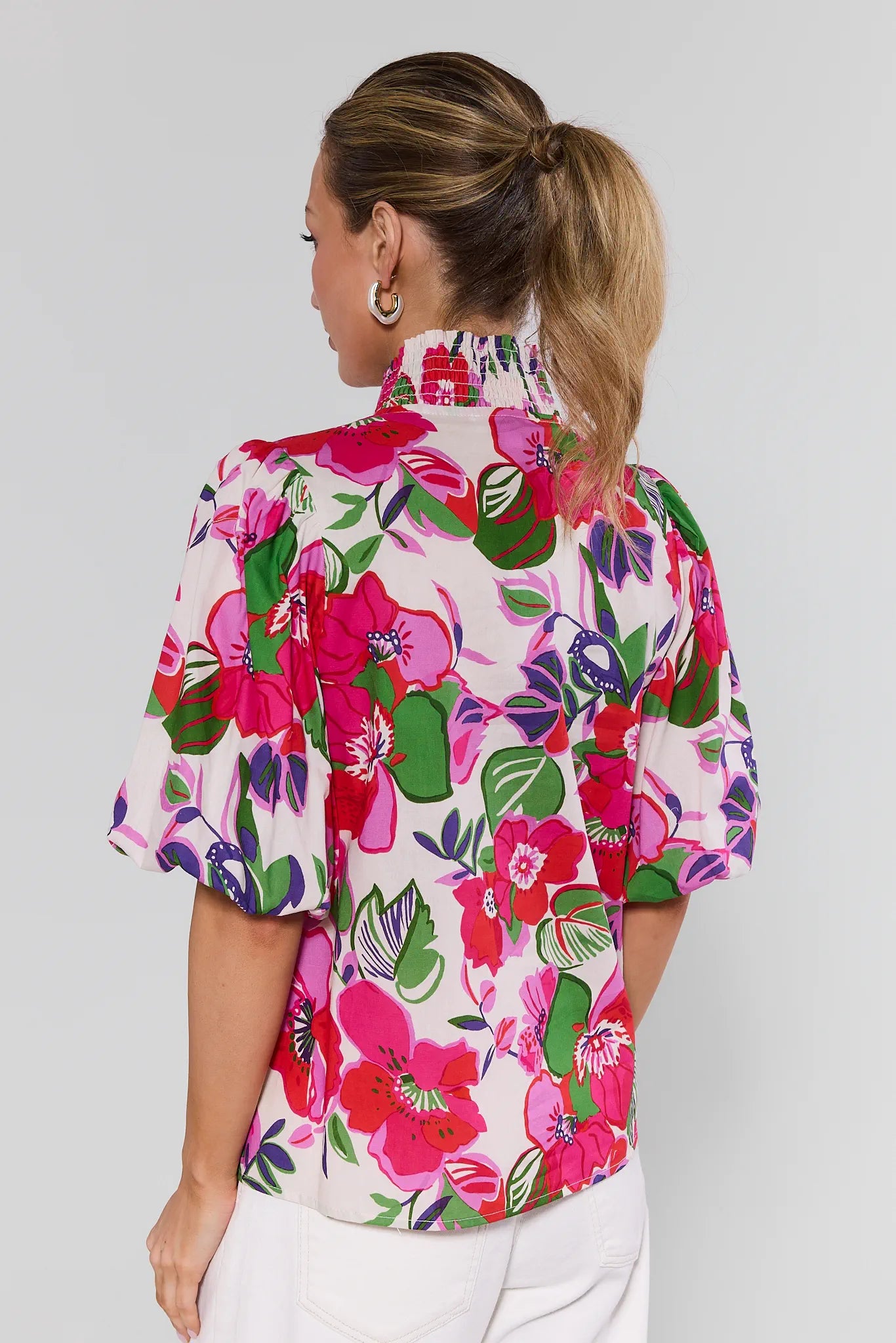 Woman wearing a colorful floral blouse on a plain background