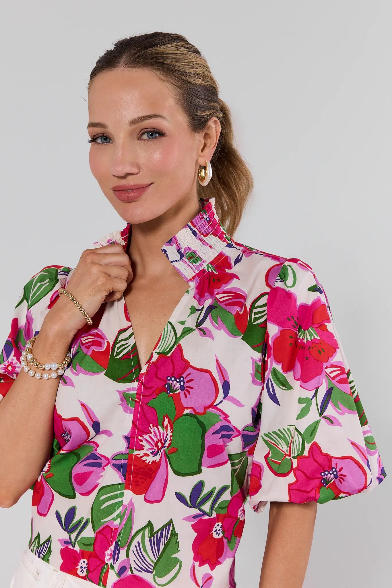 Woman wearing a colorful floral blouse against a plain background