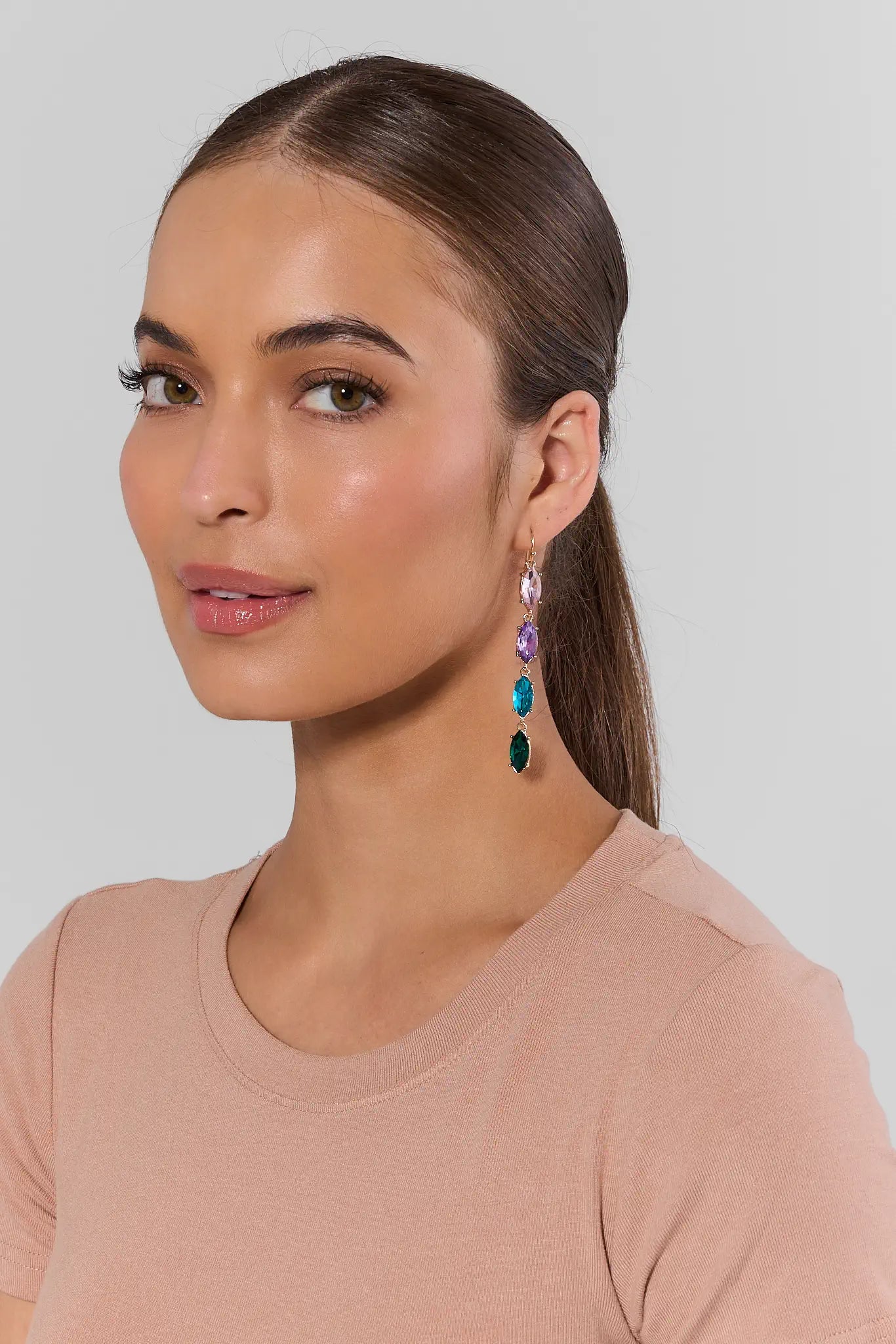Woman wearing colorful earrings against a plain background