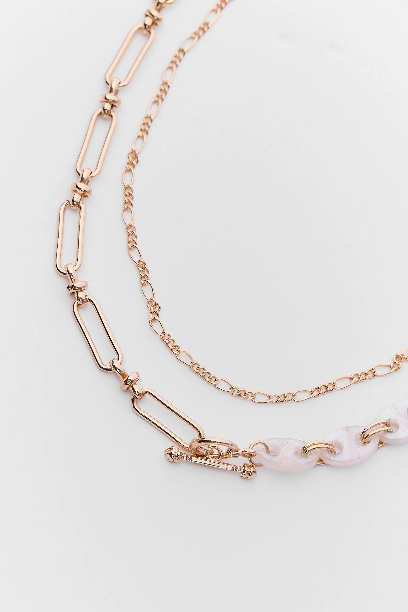 Rose gold necklace with a white bead on a light gray background