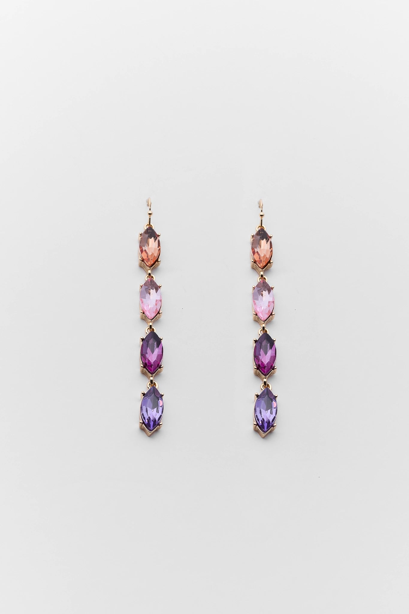 Pair of long earrings with multicolored gemstones on a light gray background