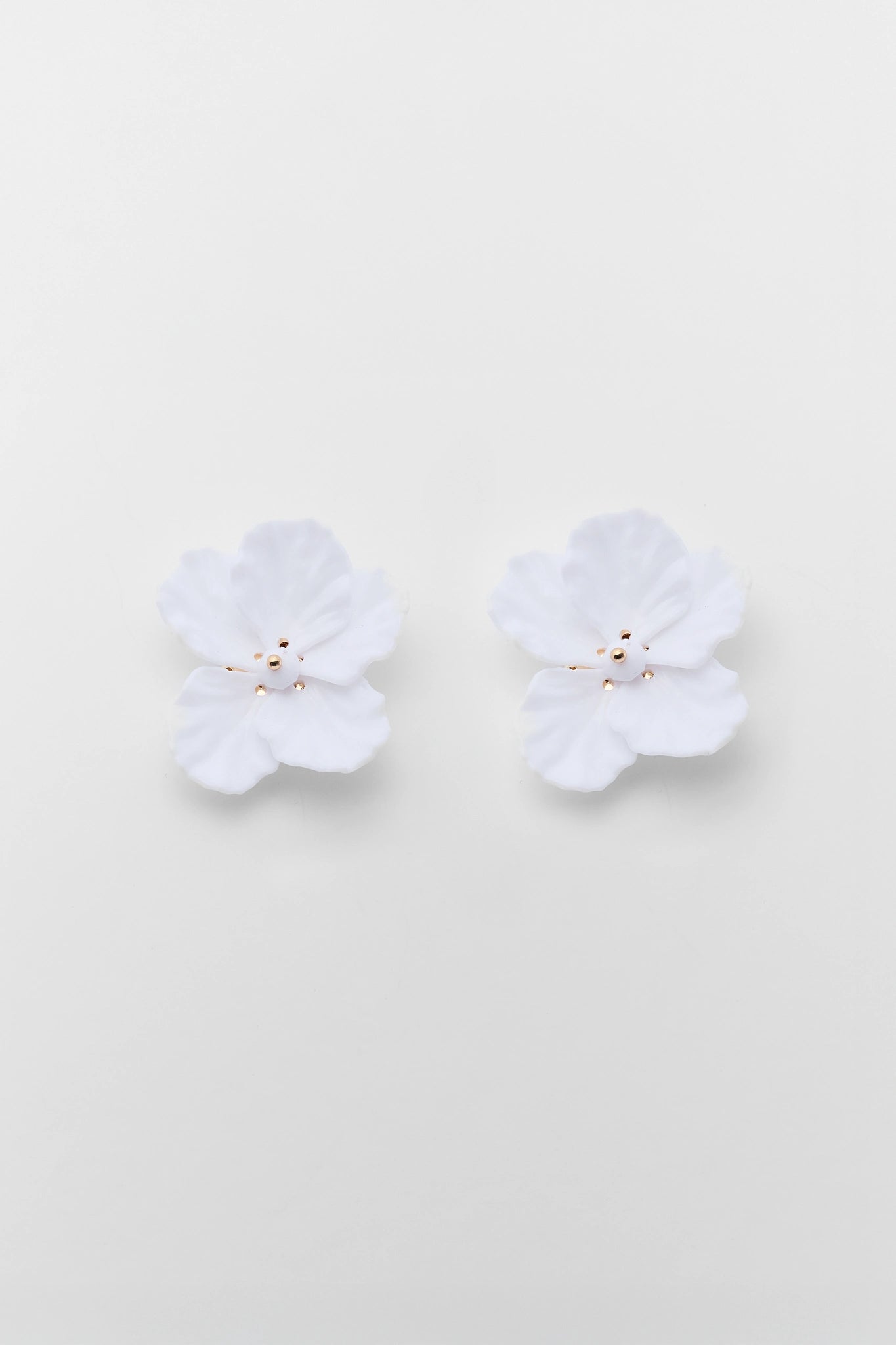 Pair of white floral earrings on a light beige background