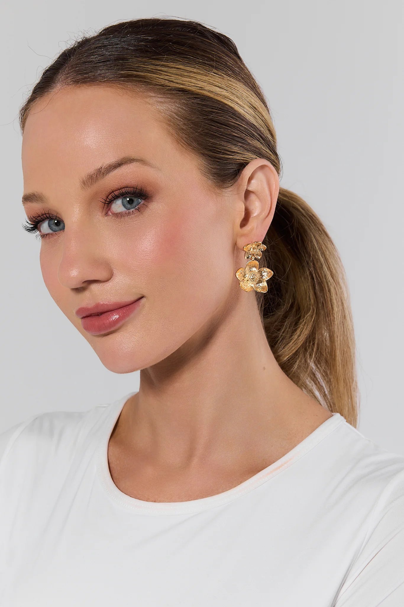 Woman wearing gold earrings against a plain background