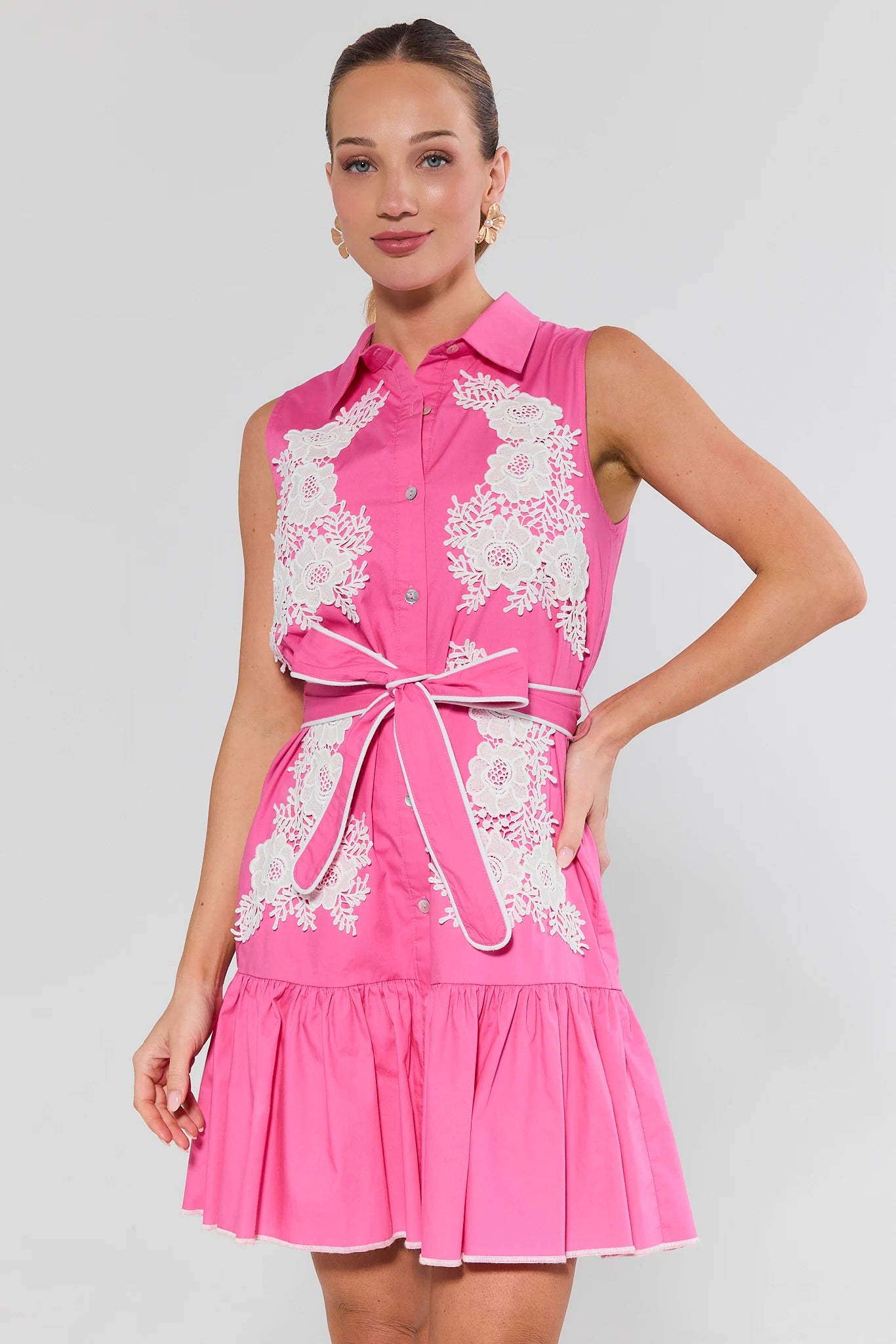 Woman wearing a pink dress with white lace details on a background
