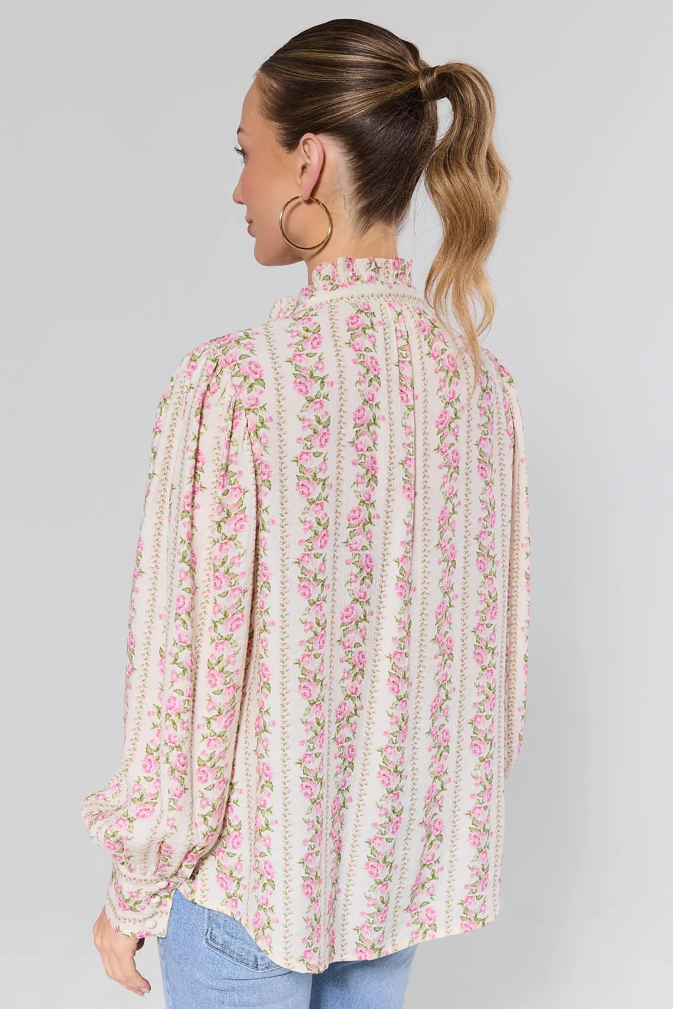 Woman standing wearing a floral blouse with a plain background