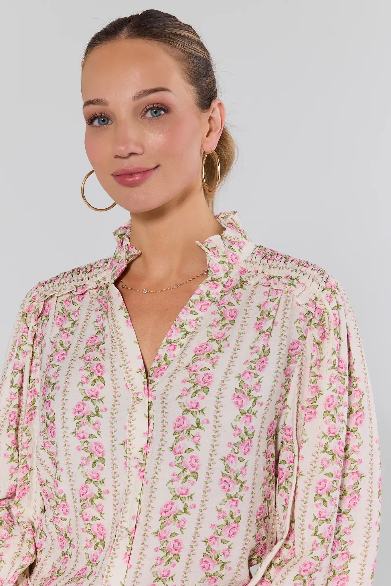 Close up of woman wearing a floral blouse with a plain background