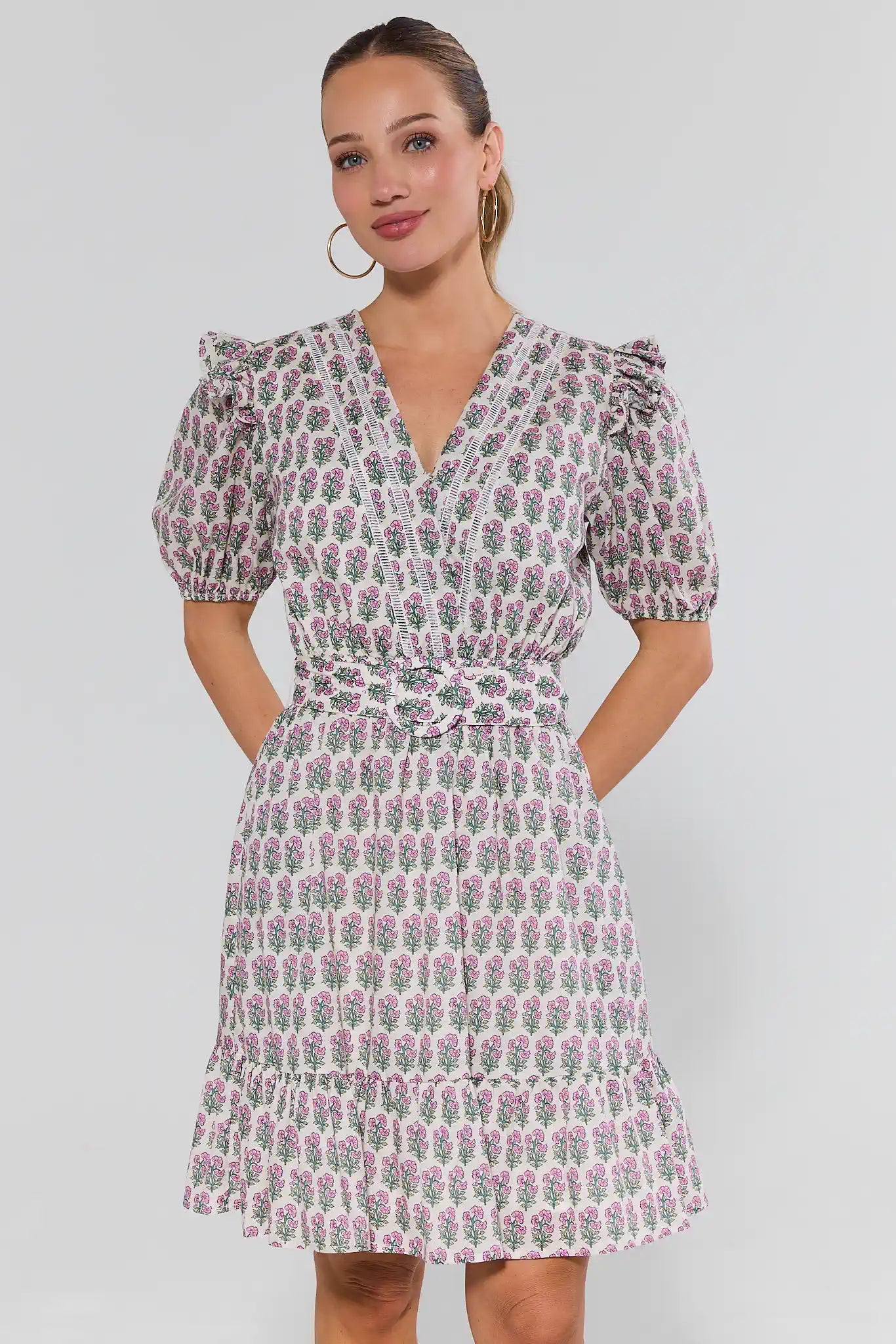 Woman wearing a floral dress with gold hoops against a background