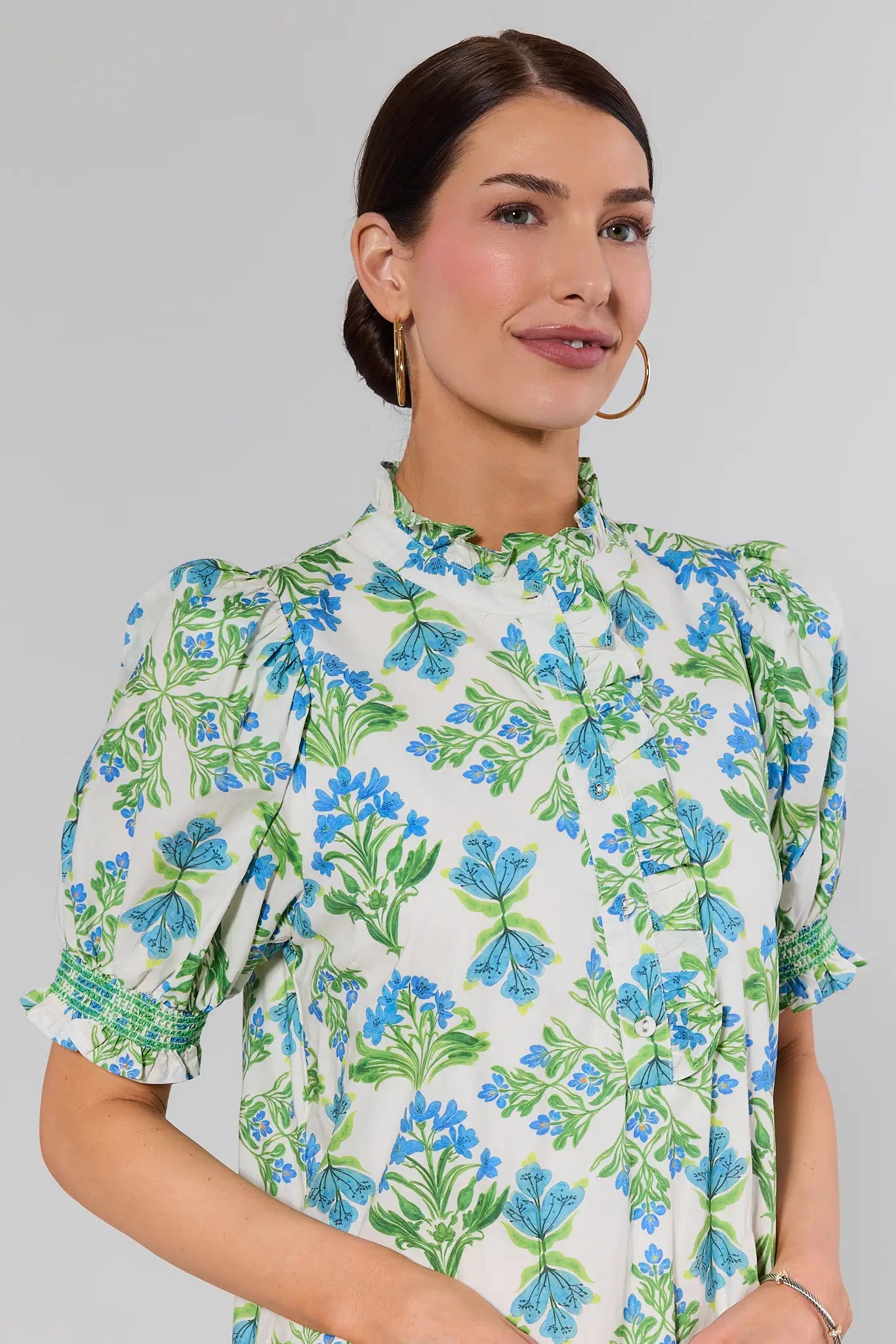 close up Woman wearing a floral dress with blue and green flowers on a plain background