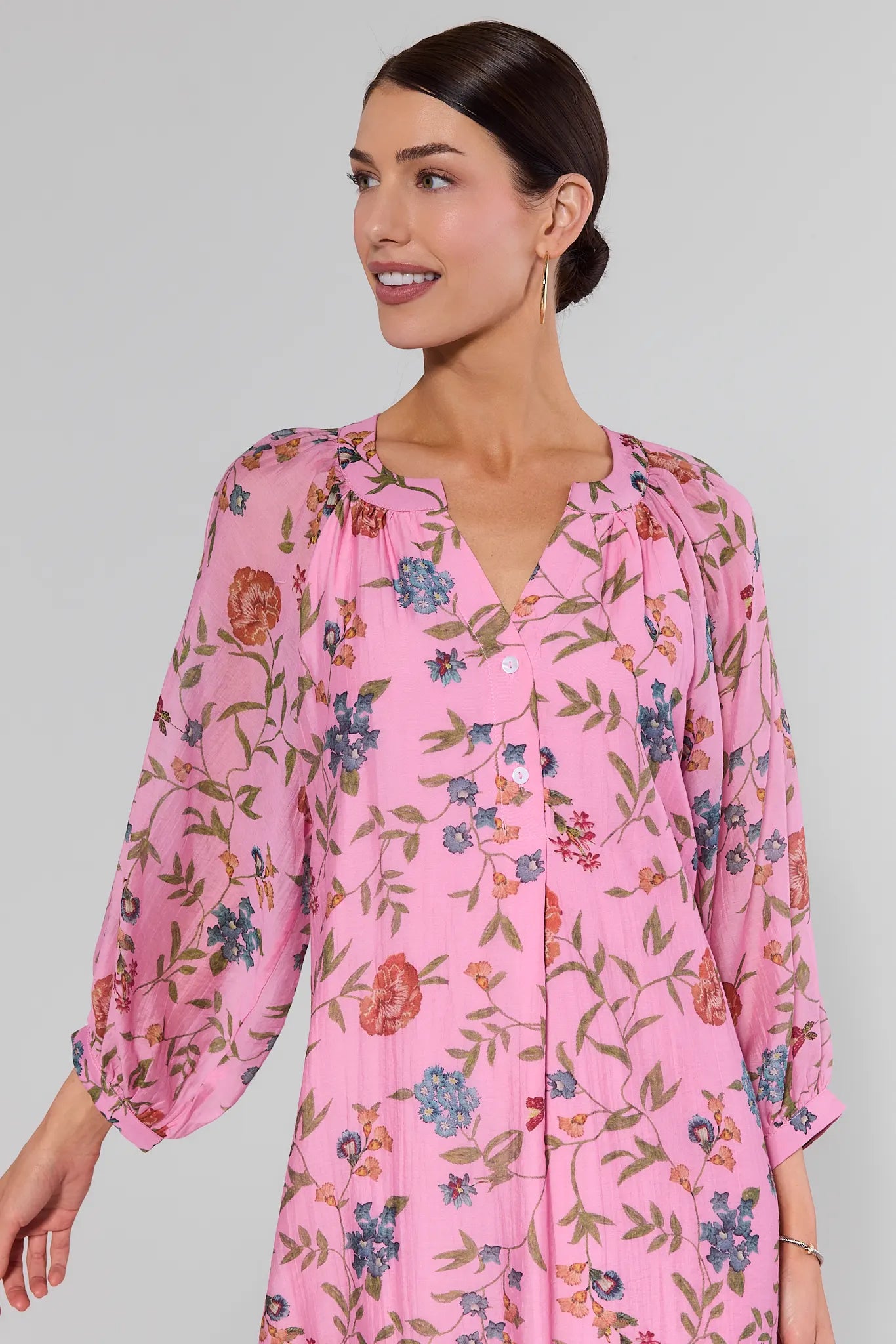 close up Woman wearing a pink floral dress against a gray background