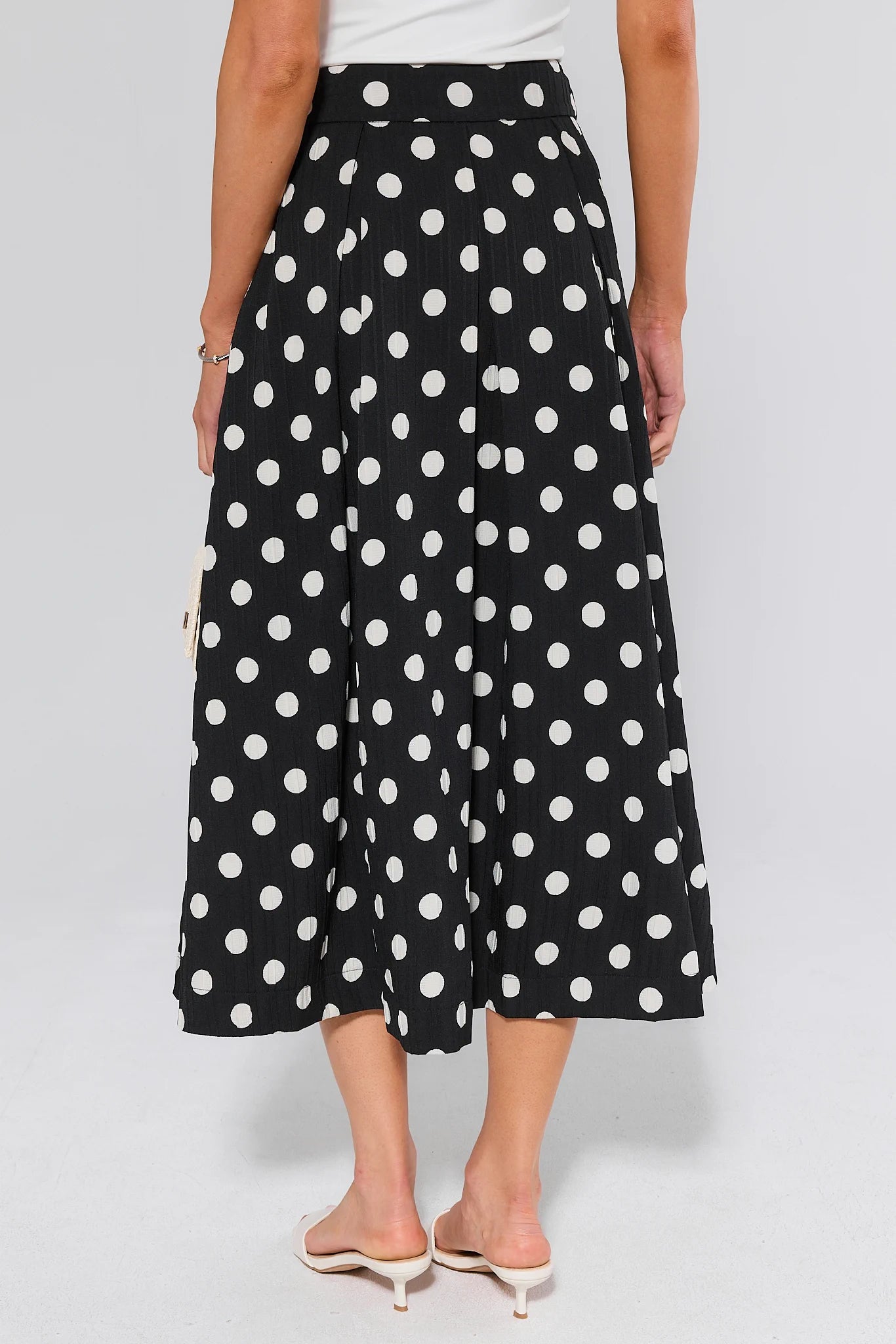 Black polka dot pants worn by a woman on a white background