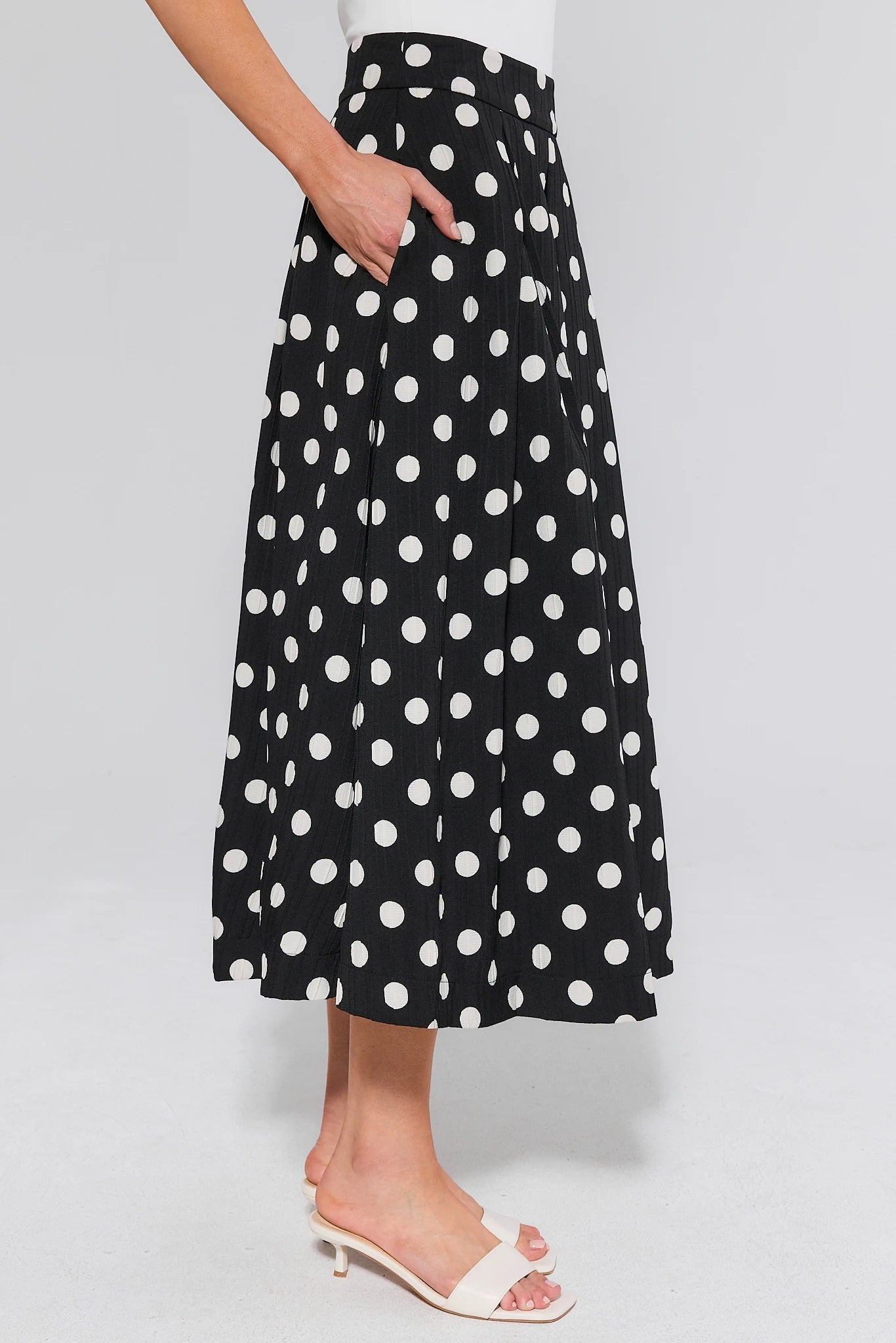 Black polka dot skirt and heels worn by a person on a white background