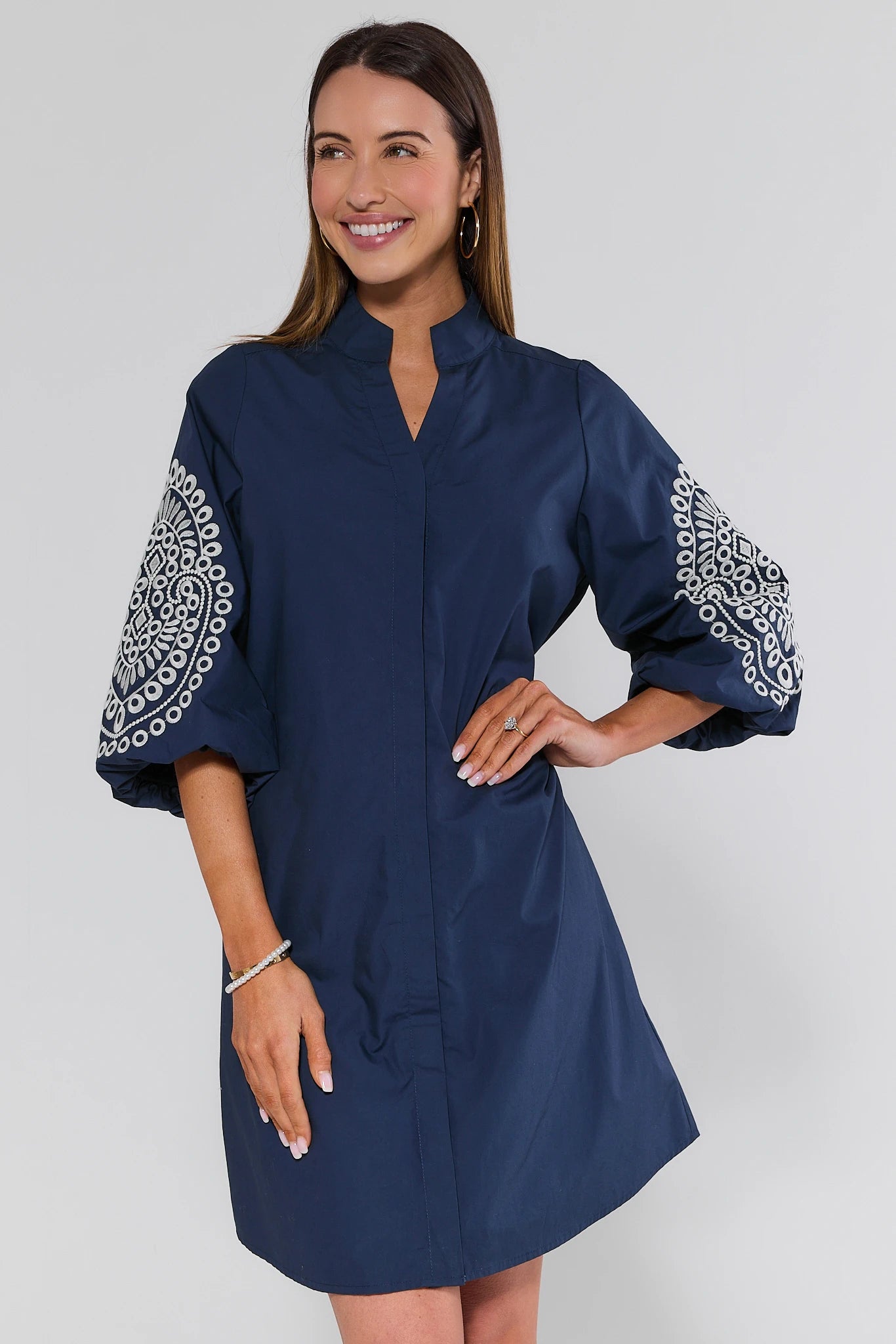 Woman wearing a navy dress with patterned sleeves on a white background