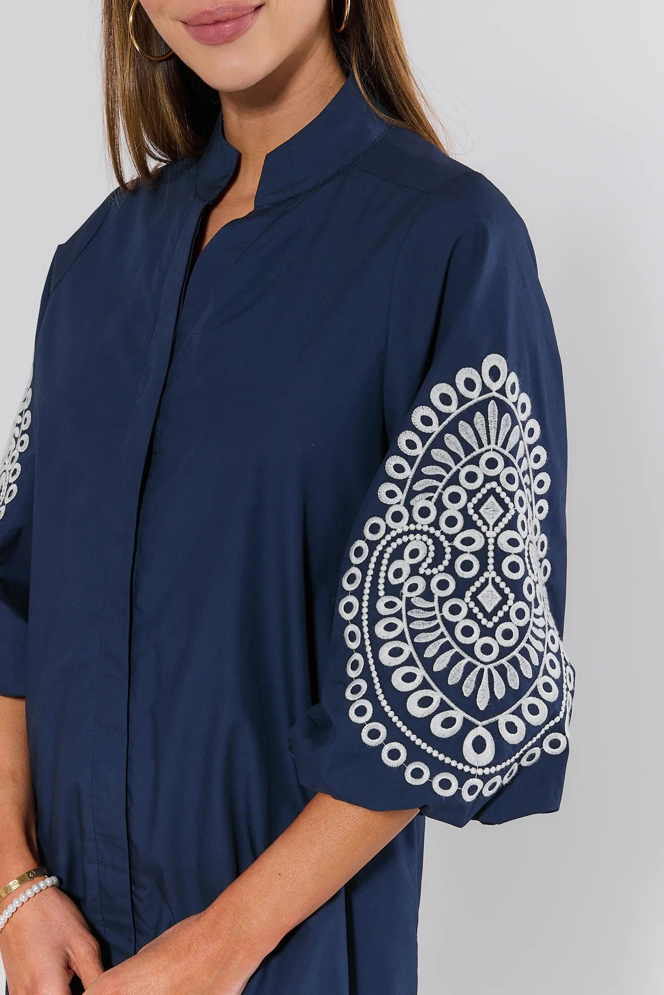 Navy blue top with white lace detailing on sleeves against a light gray background